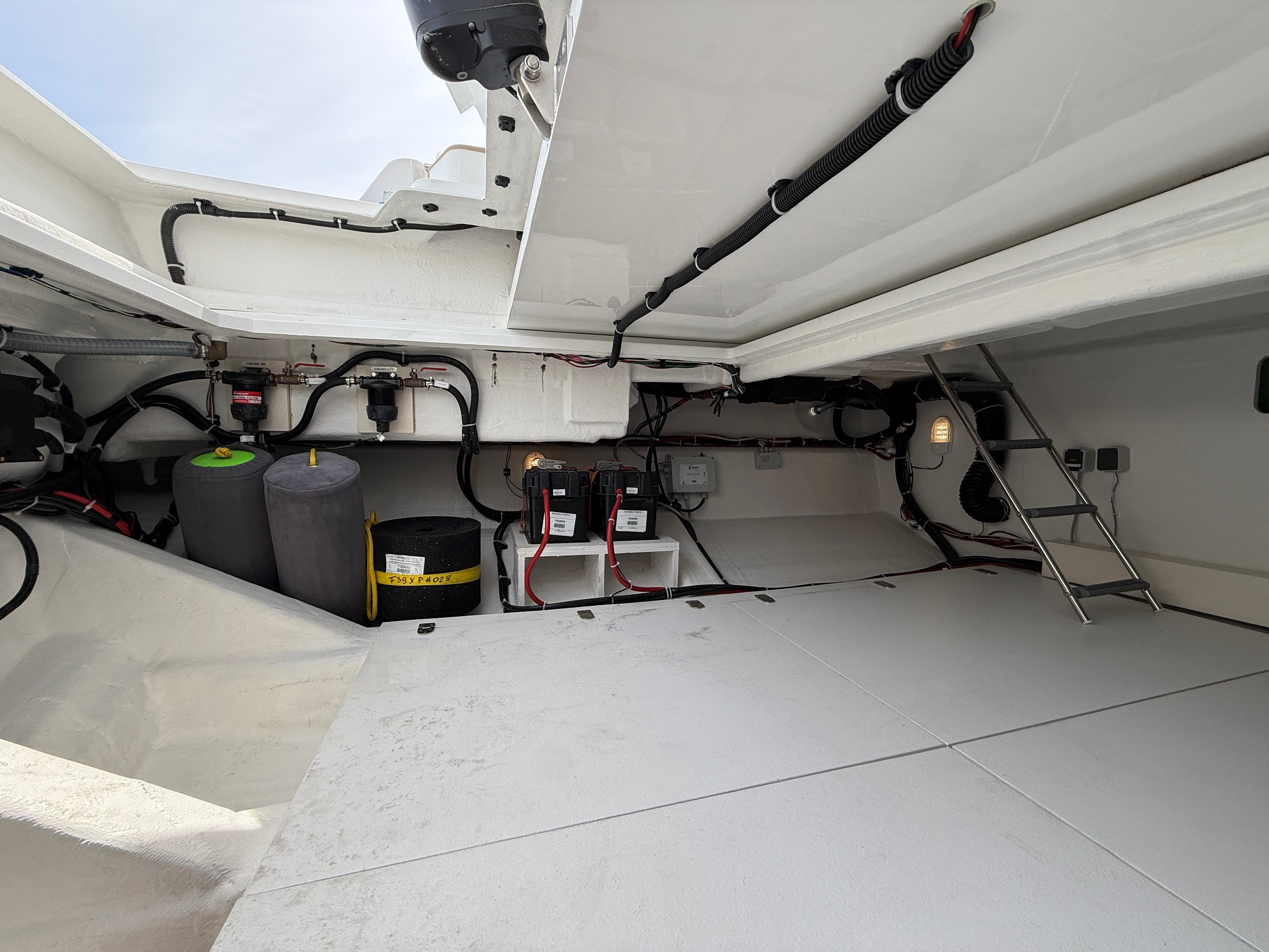 Engine compartment of 2025 Fjord 39 XP yacht, showcasing wiring and storage space.