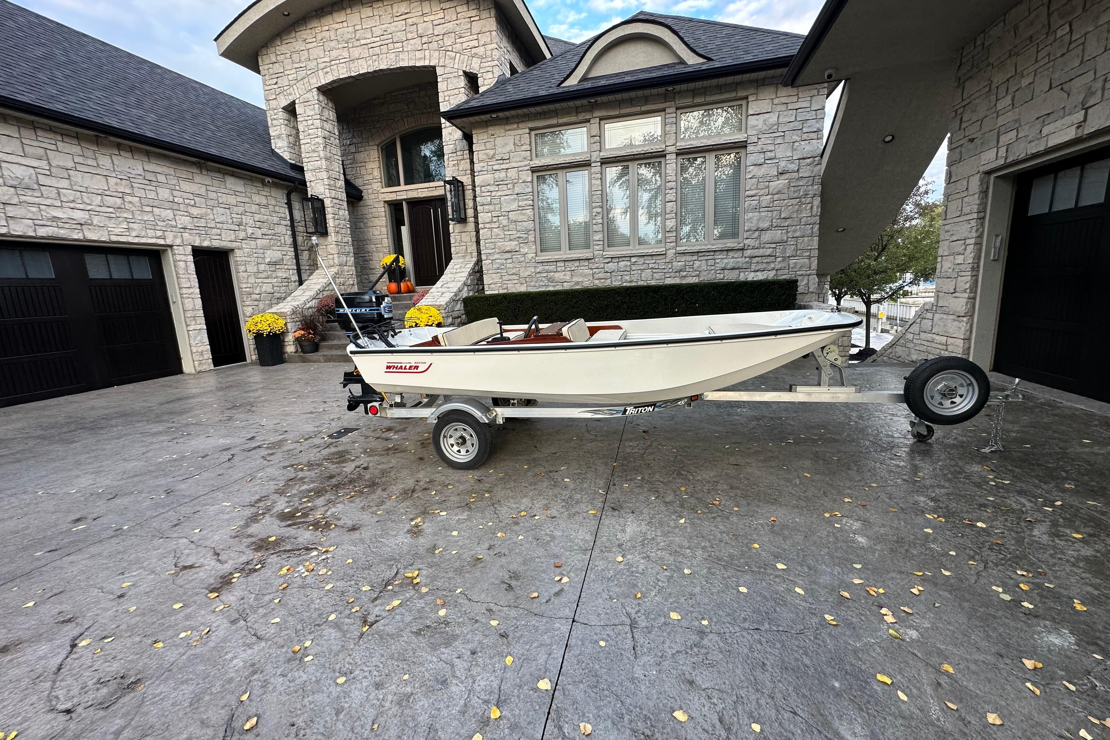 1975 Boston Whaler Classic boat on trailer in front of a stone house.