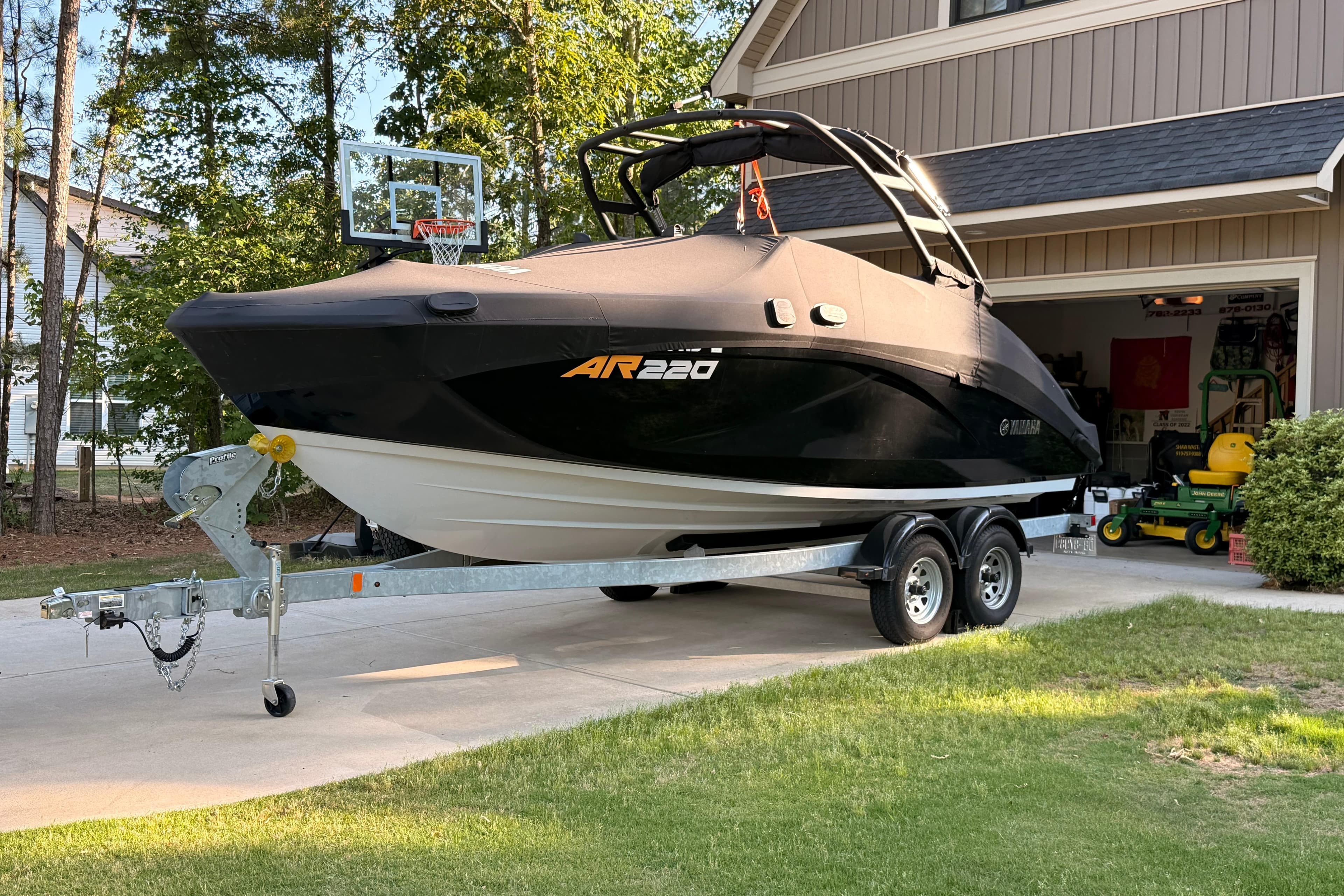 2024 Yamaha Boats AR220 on trailer in driveway, covered and ready for transport.