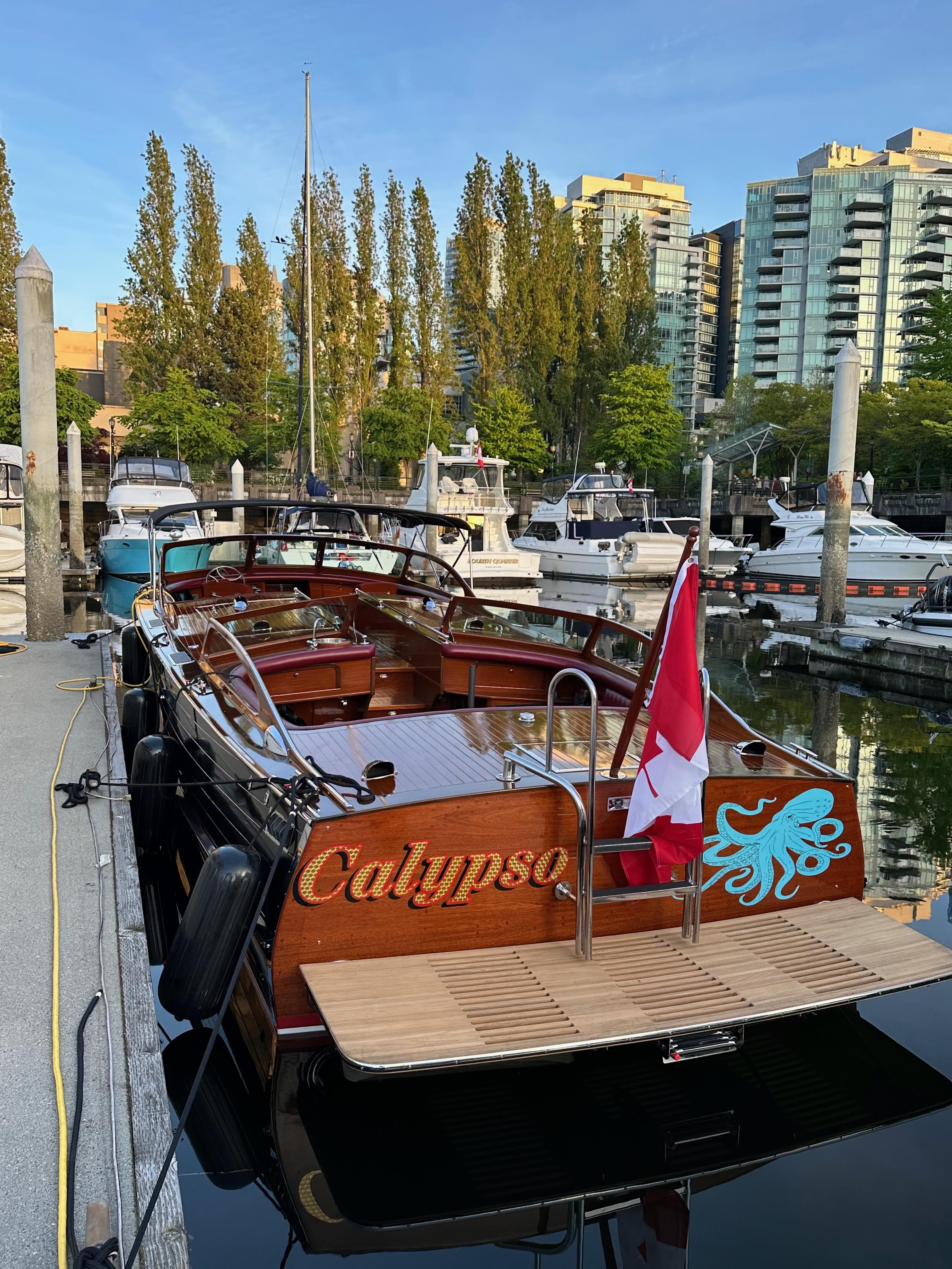 1946 Stephens Triple Cockpit boat "Calypso" docked, featuring a Canadian flag and waterfront view.