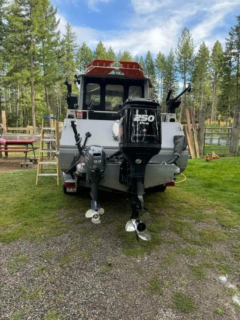 Rear view of a 2005 ACB 27 boat with dual outboard motors in a wooded area.