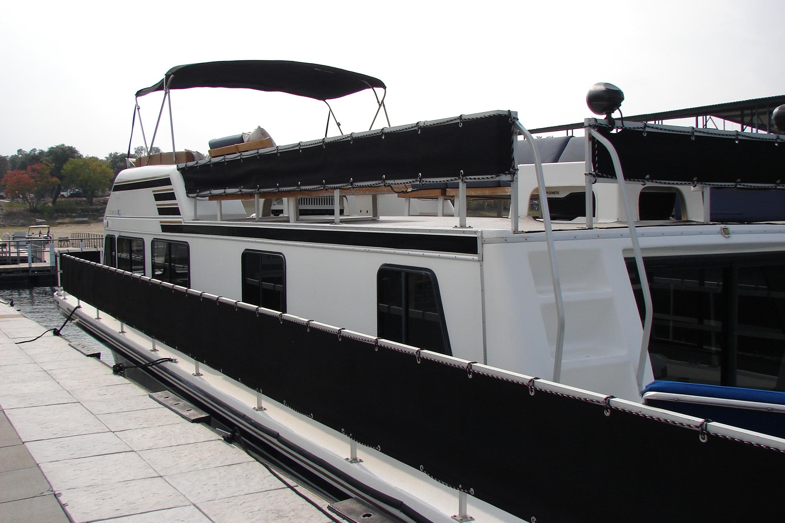 1997 Gibson 47 Sport Houseboat docked at marina, featuring upper deck and canopy.