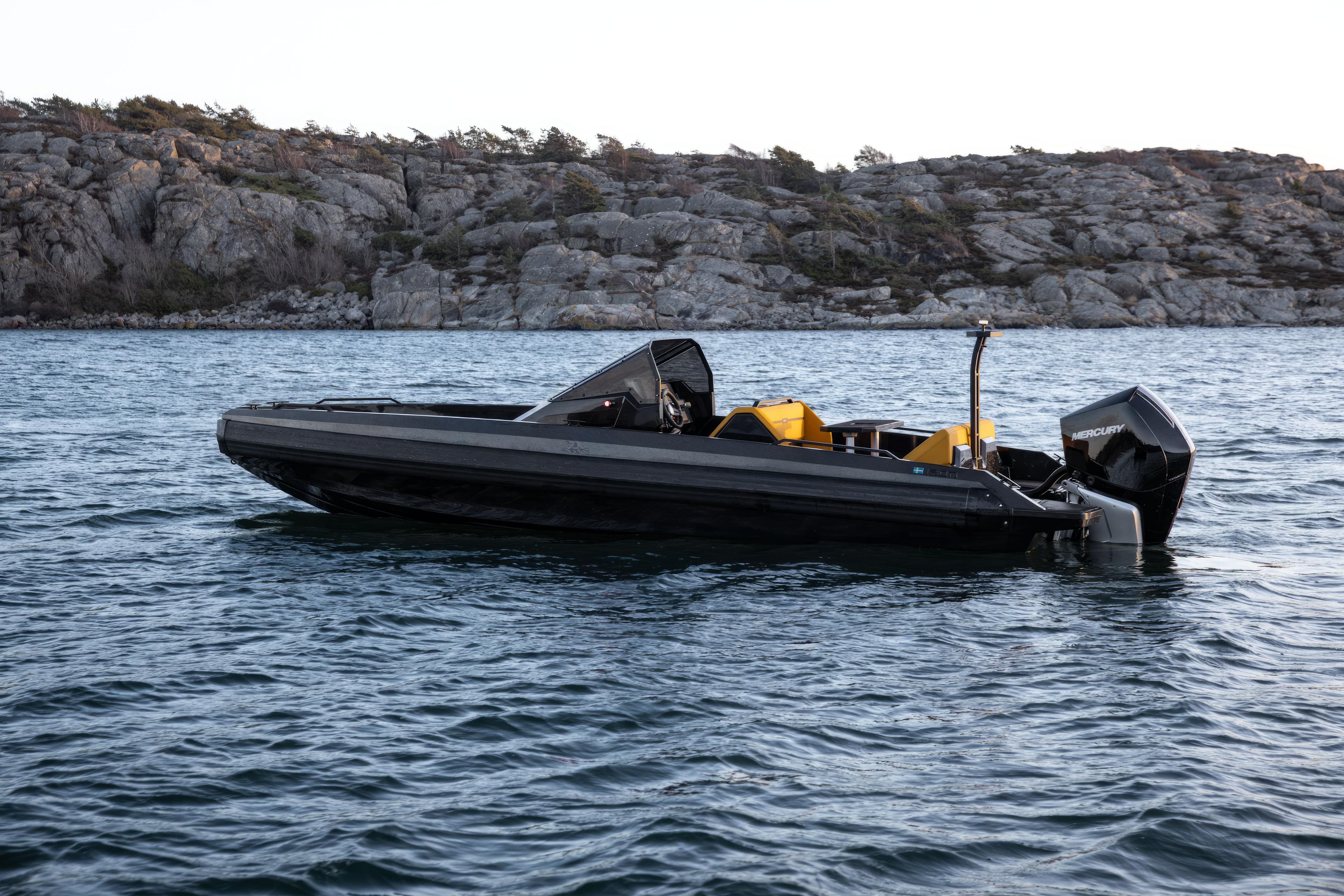 2026 Iron 767 T-top boat on water near rocky shoreline.
