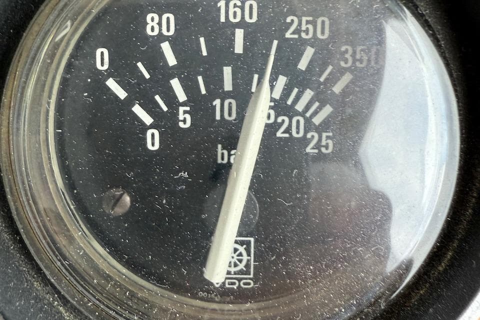 Close-up of a vintage Nauset Flybridge Cruiser pressure gauge, displaying bar measurements.