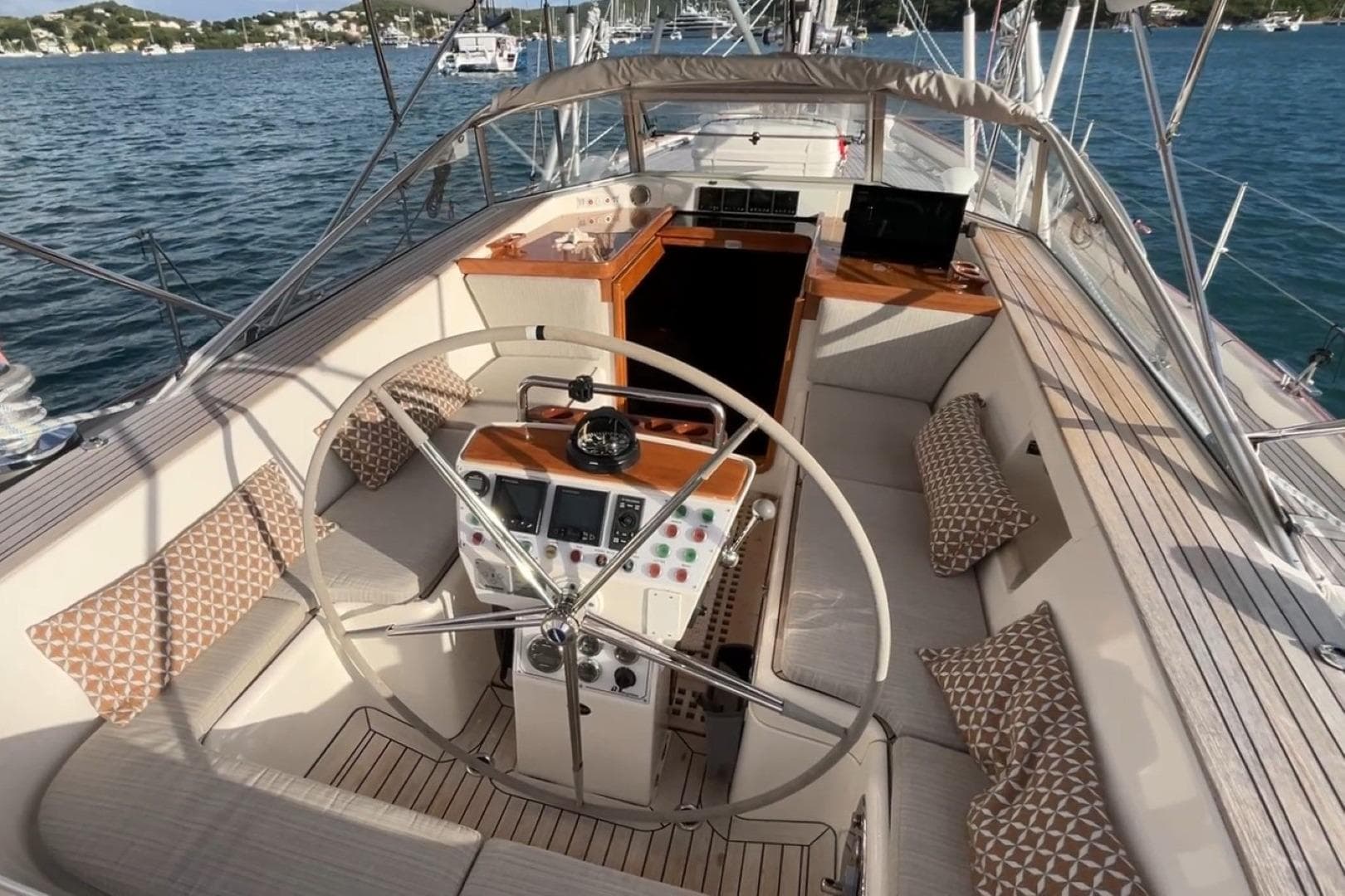 Luxurious 2009 Hallberg-Rassy 54 yacht cockpit with steering wheel and seating, docked in scenic waters.