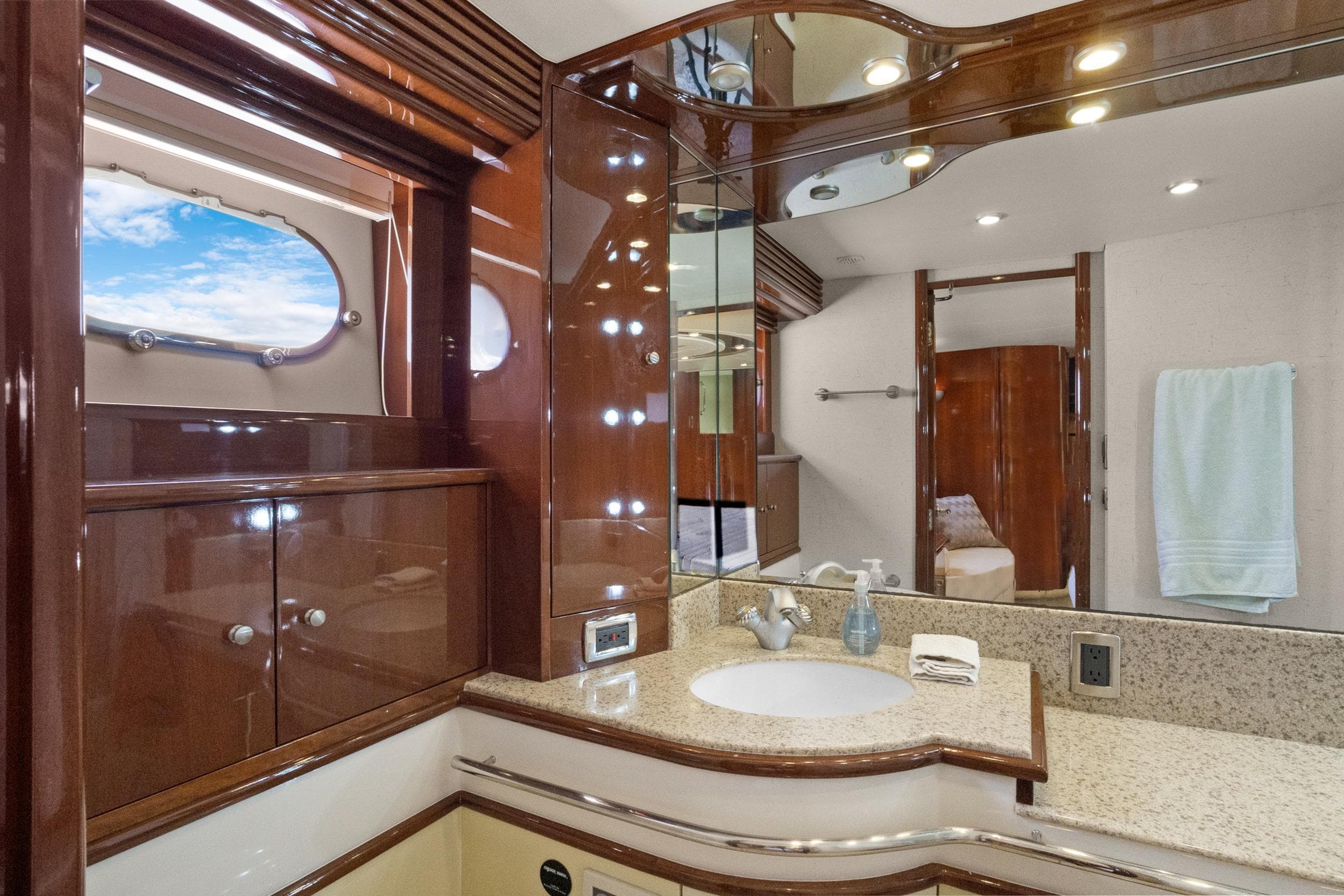 Luxurious 2008 Marquis 690 yacht bathroom with elegant wood finishes and granite countertop.