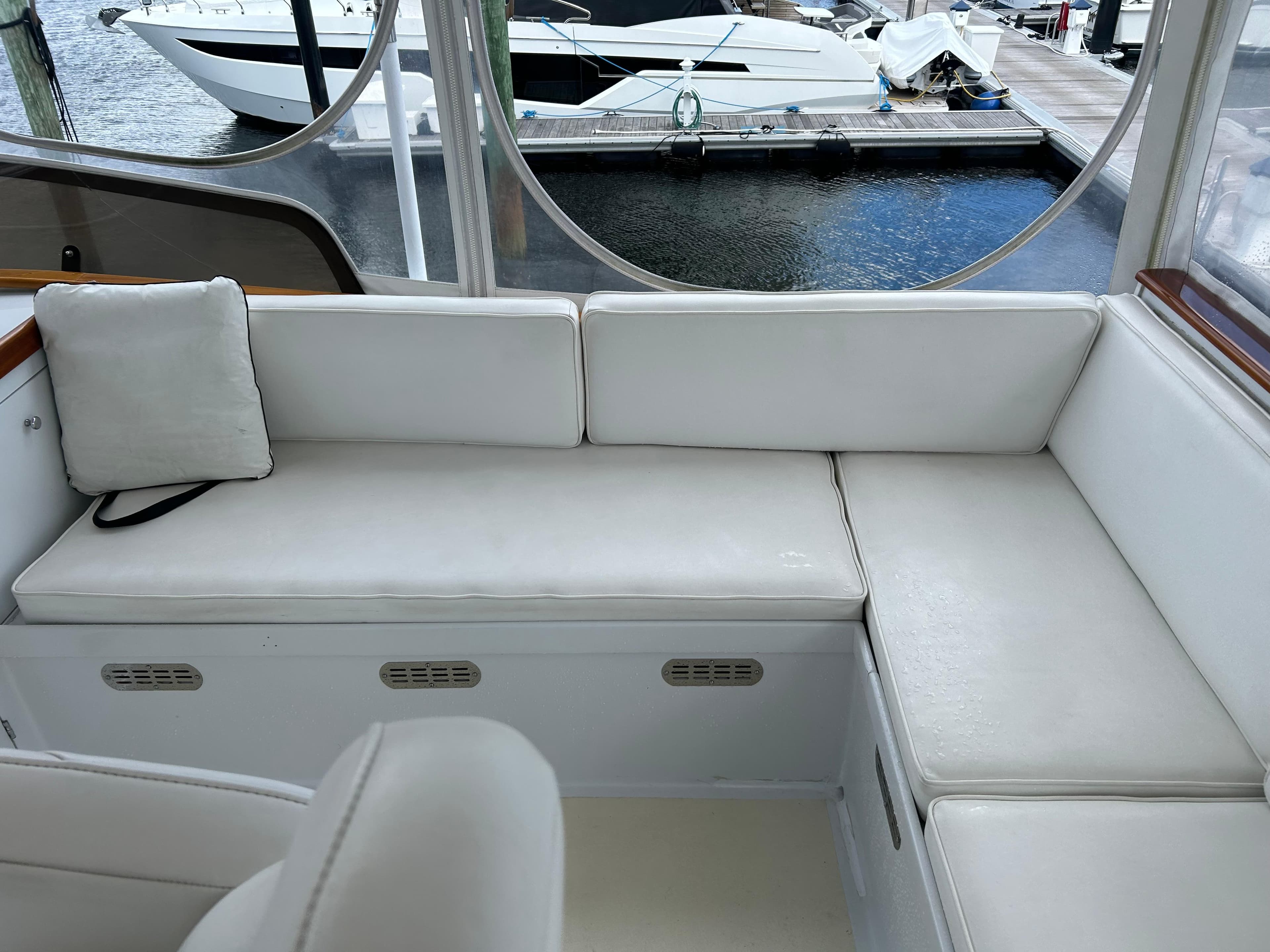 1987 Lyman-Morse Downeast Flybridge interior with white seating, docked boats visible outside.