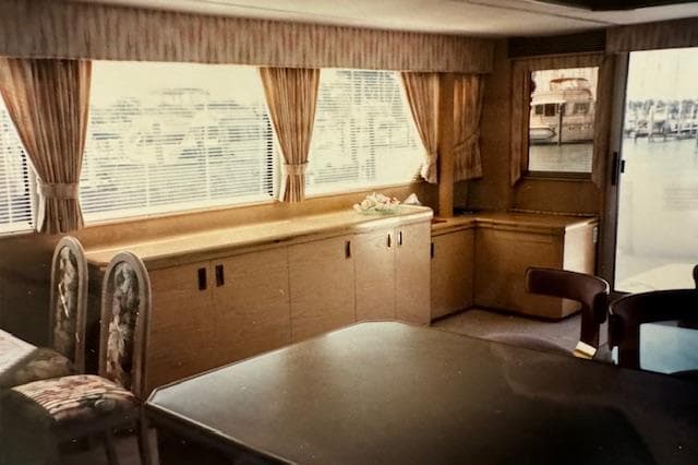 Interior of 1990 Motor Yacht 70 Brata with elegant wood furnishings and large windows.
