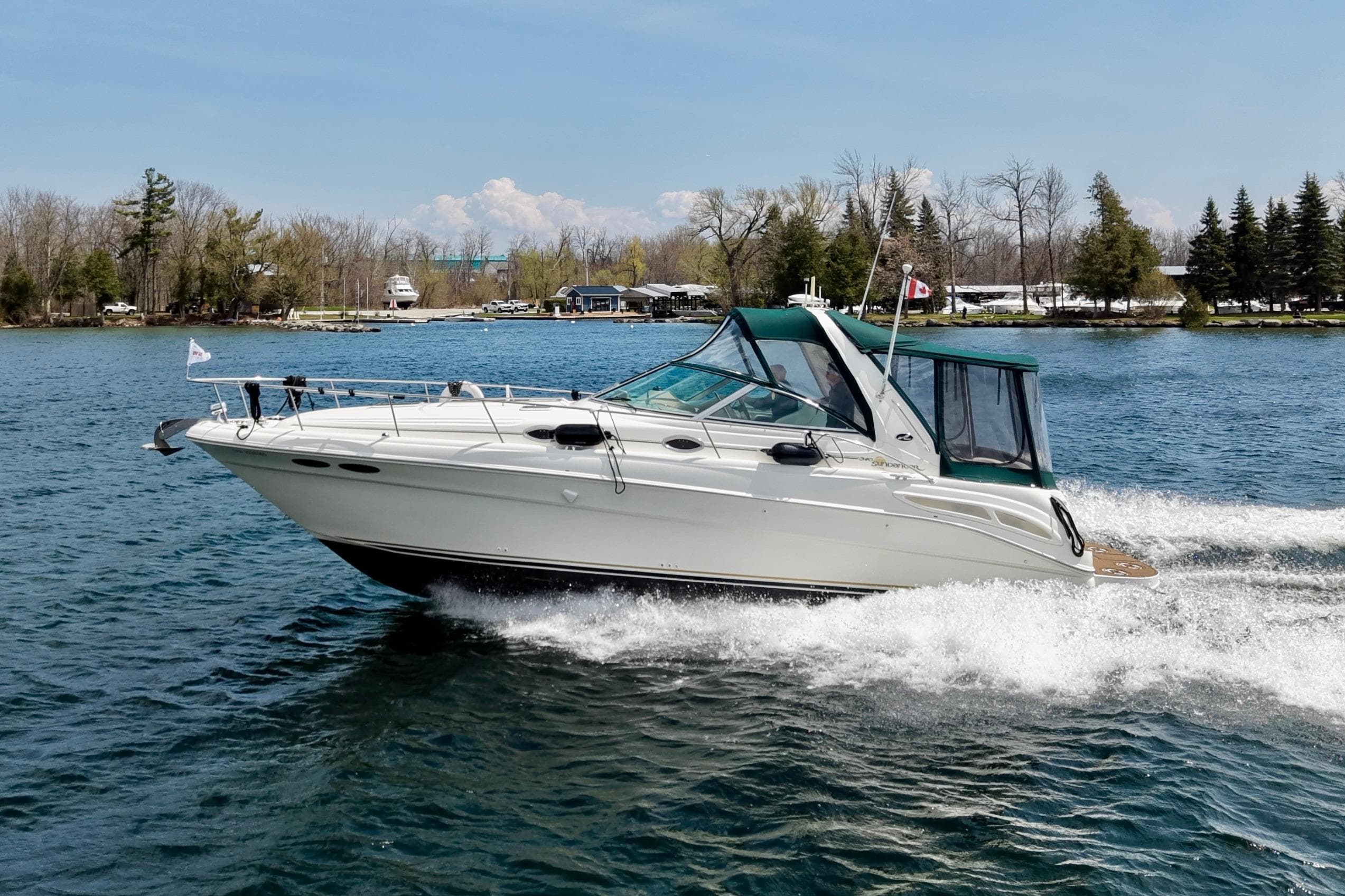 2002 Sea Ray 340 Sundancer cruising on a scenic lake with trees in the background.