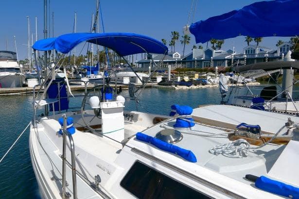 1989 Catalina 34 sailboat docked in a sunny marina with blue canopies.