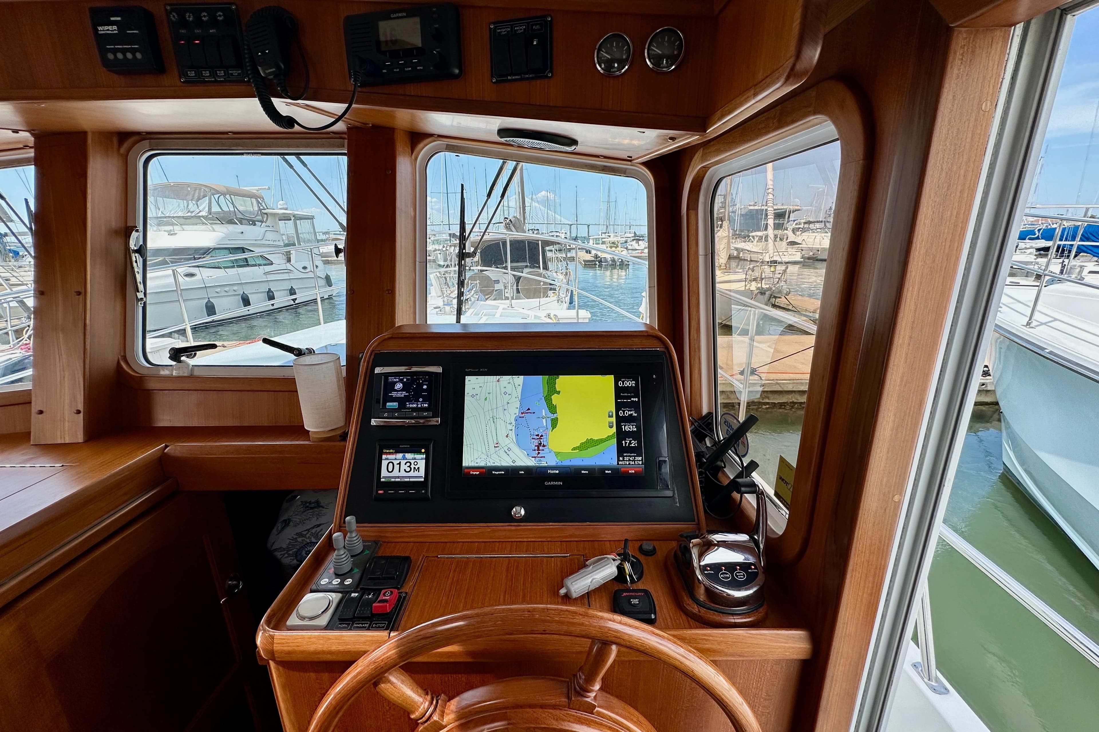 2016 Helmsman Trawlers 38 Pilothouse interior with navigation equipment and marina view.