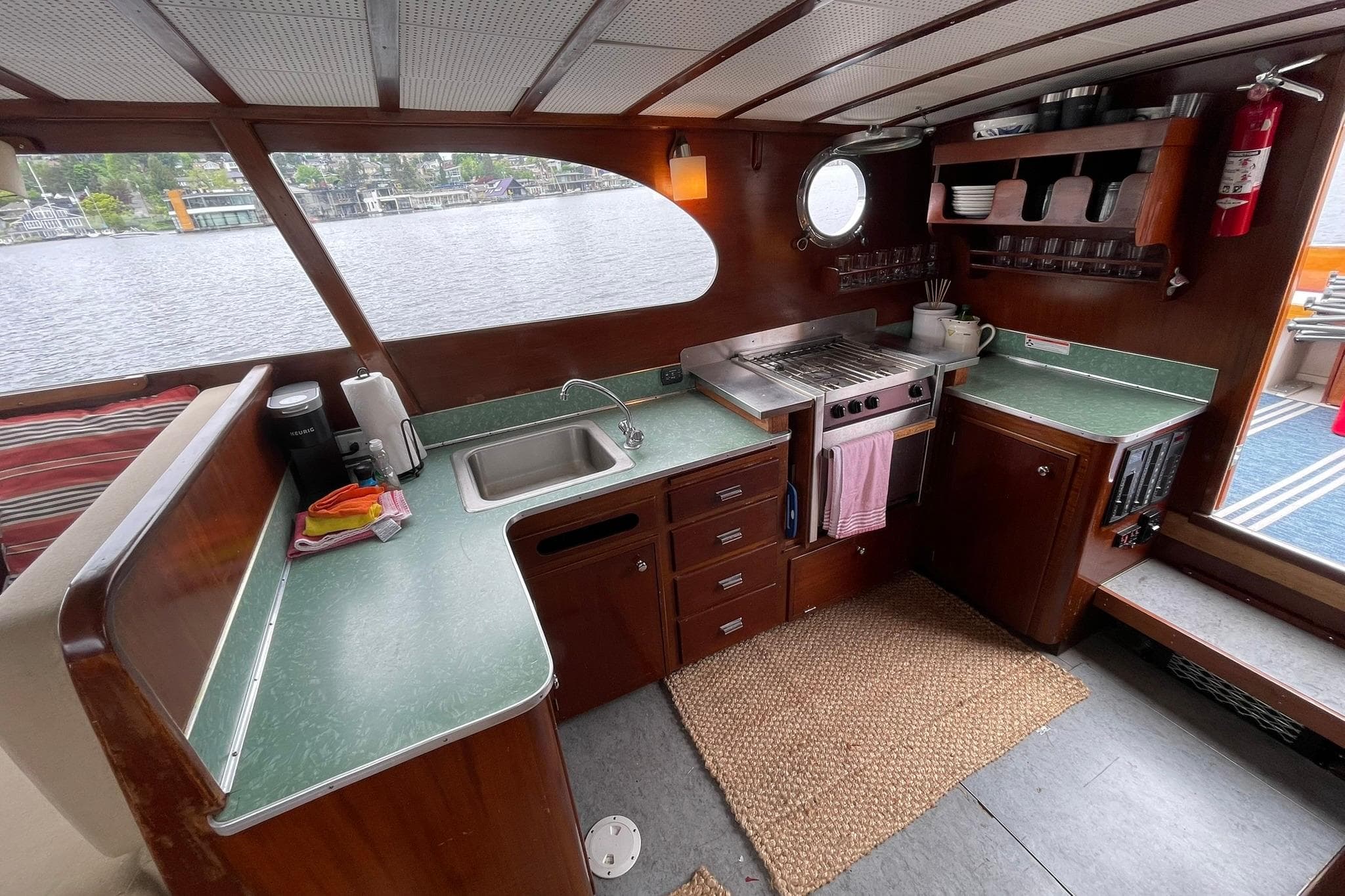 Vintage 1948 Grandy 34 boat kitchen with green countertops, stove, and sink by a window.
