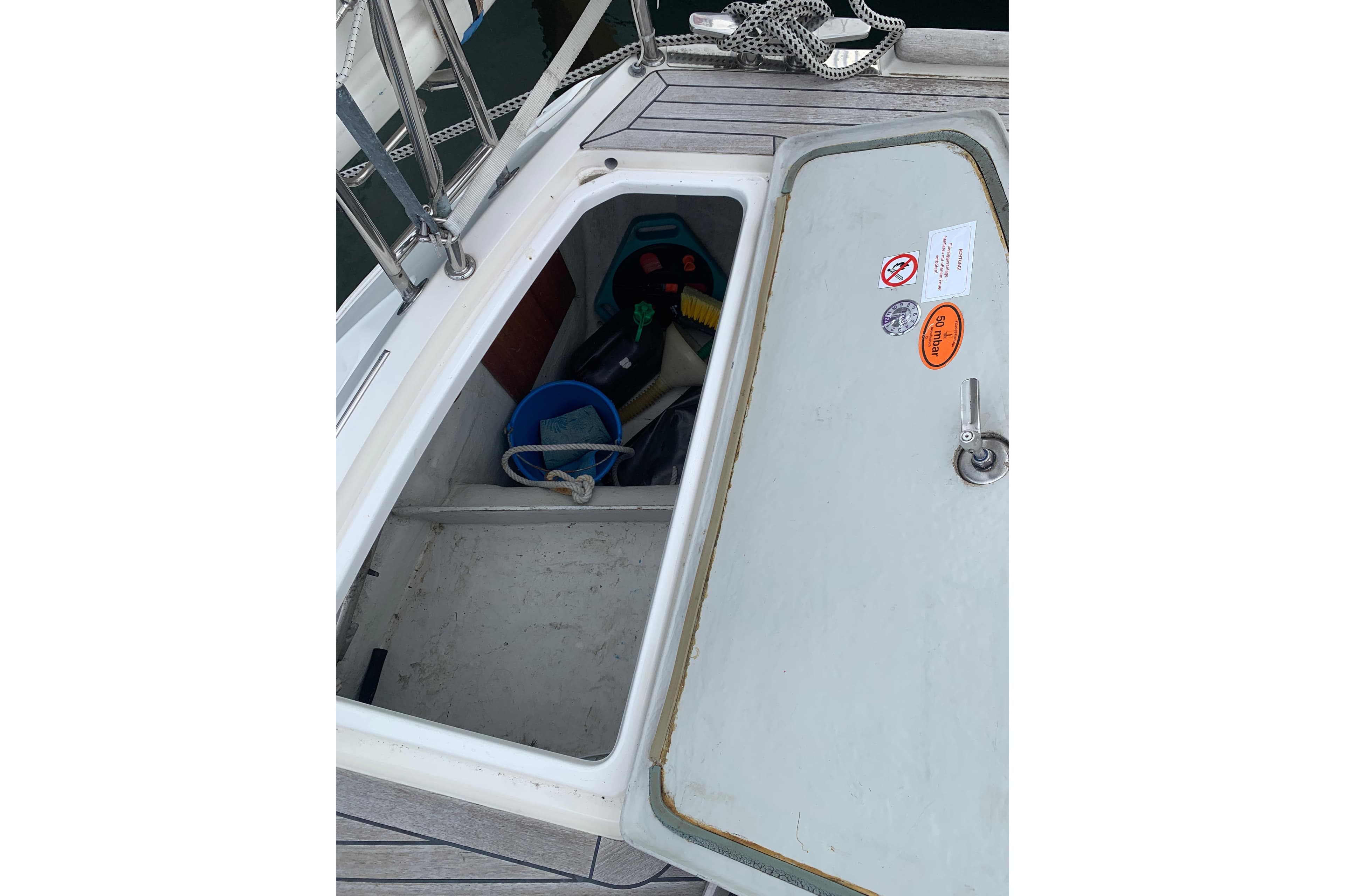 Open storage compartment on a 2000 Sunbeam 37 boat deck, containing cleaning supplies.