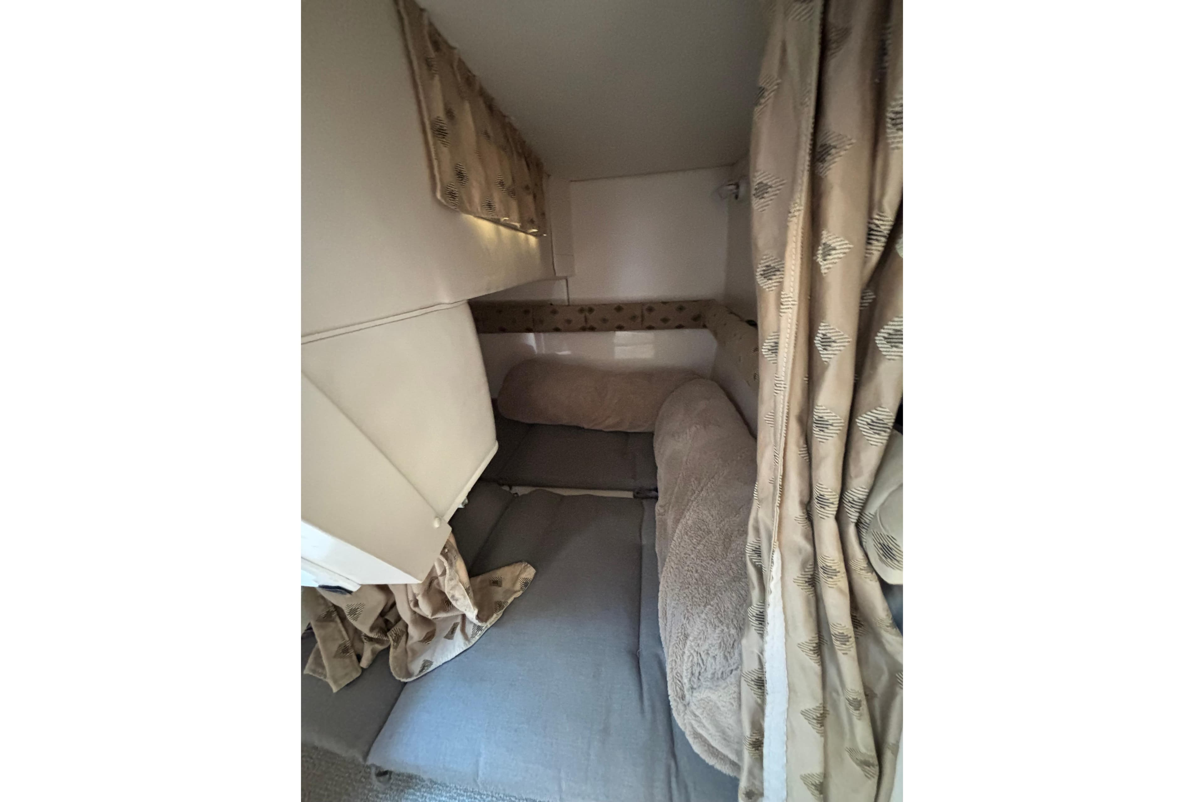 Interior cabin of 2001 Wellcraft 2800 Martinique boat with cozy bedding and curtains.