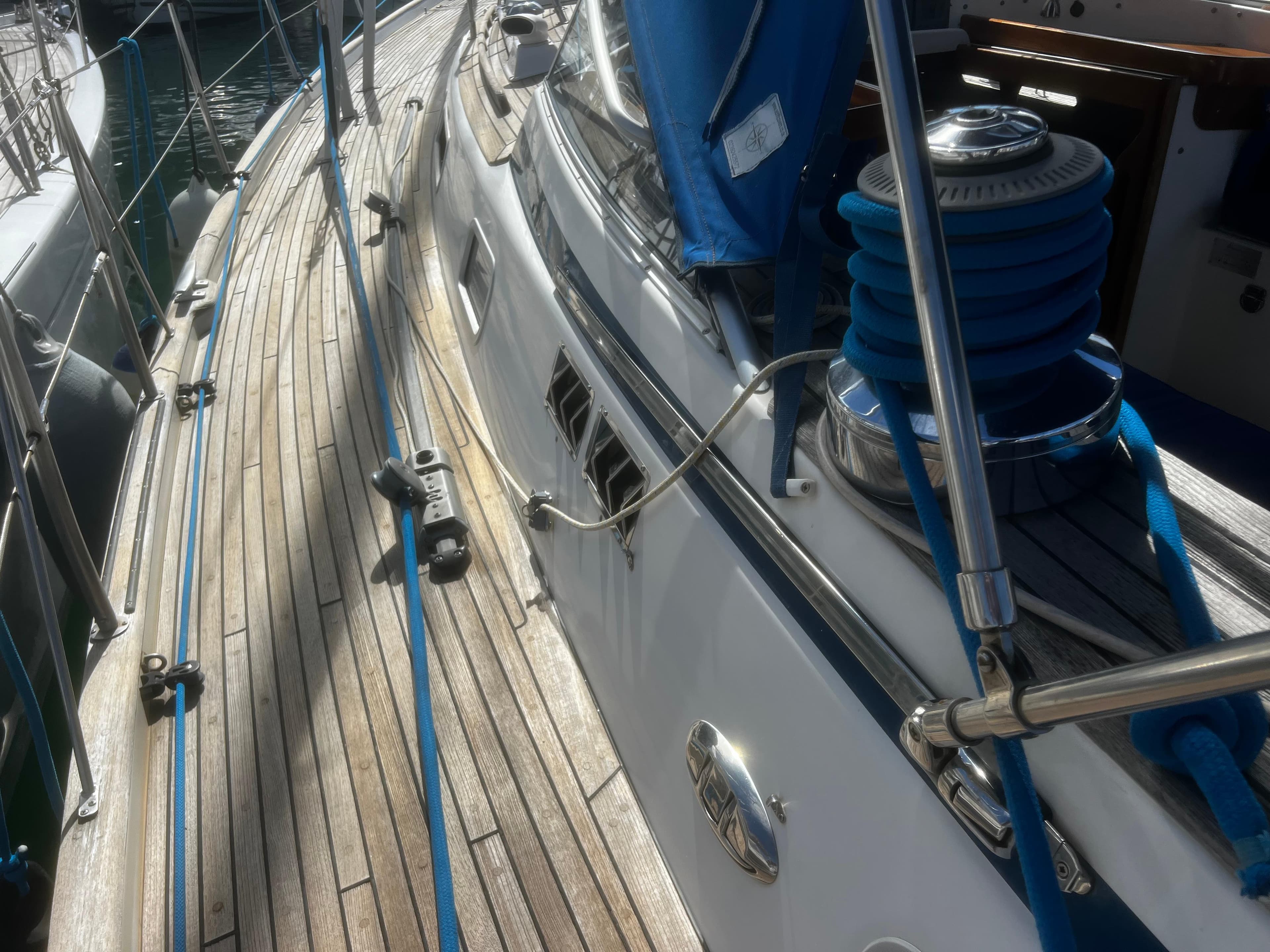 Deck view of a 2001 Hallberg-Rassy 42 sailboat with teak wood and blue accents.