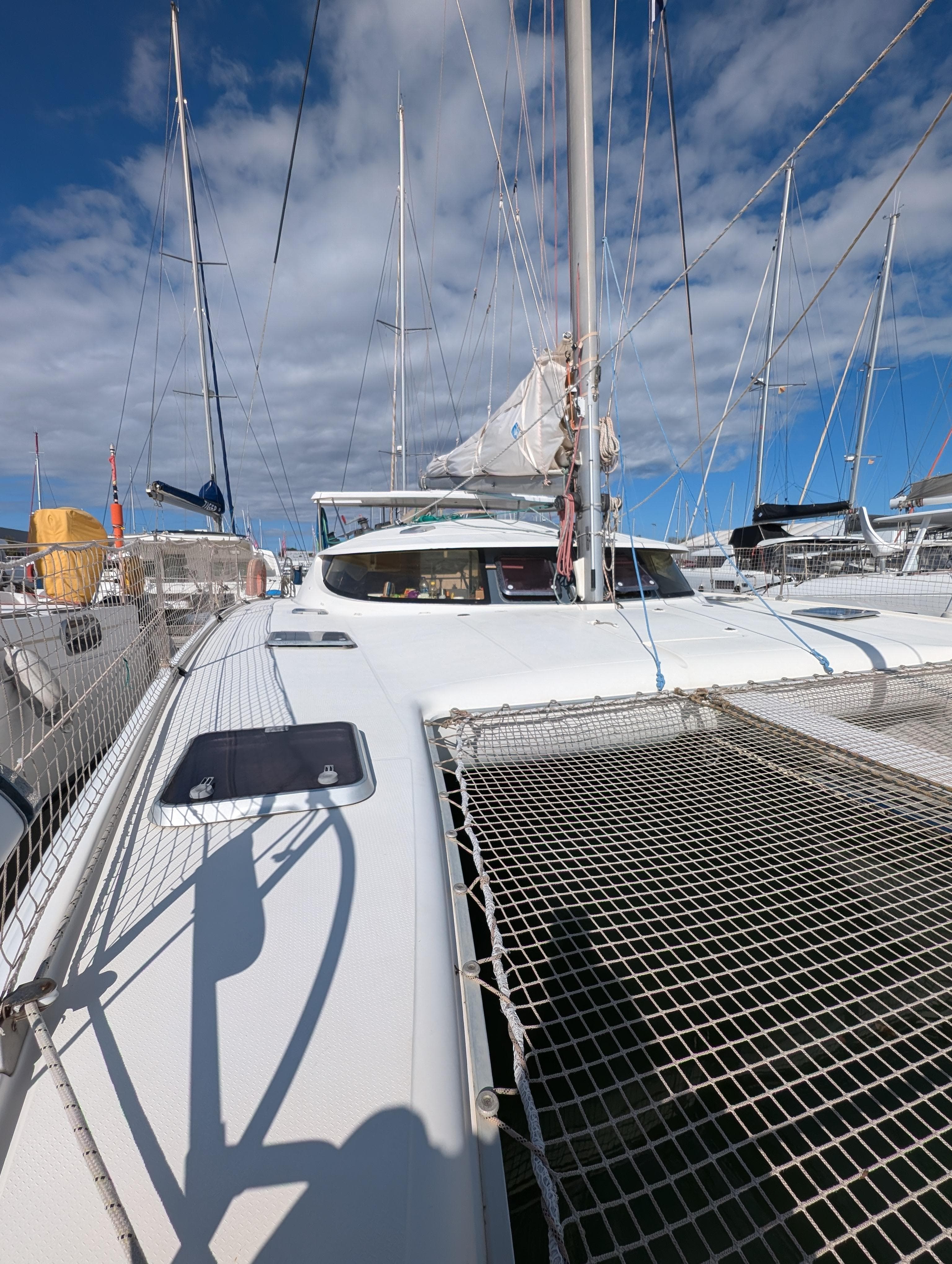 1999 Fountaine Pajot Athena 38 catamaran docked, showcasing deck and rigging under blue sky.