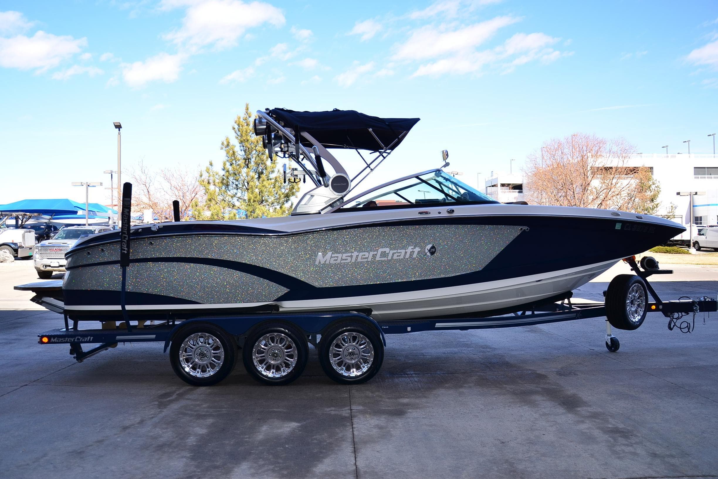 2019 MasterCraft X26 boat on trailer, parked outdoors under a clear blue sky.