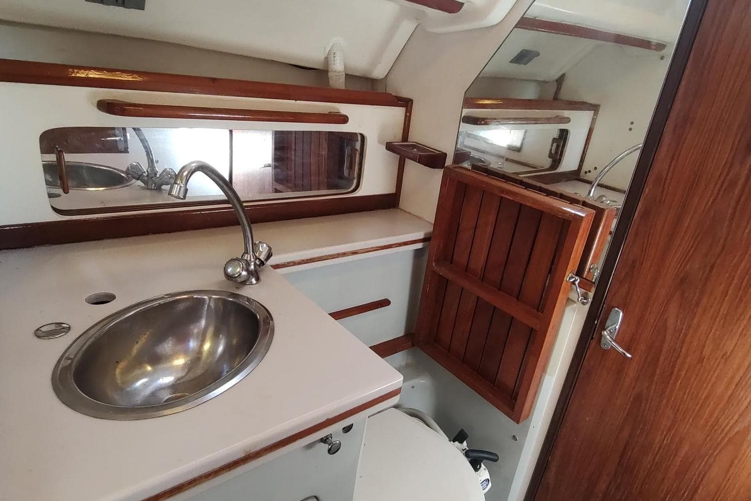 1987 Hunter 37 Legend yacht bathroom with sink, mirror, and wooden cabinetry.