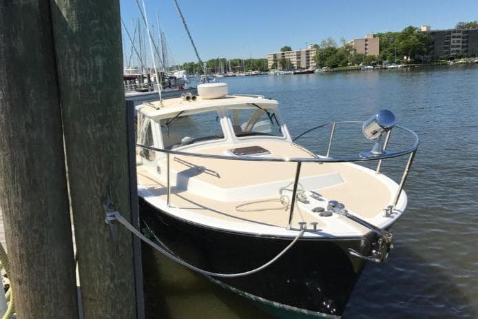 2009 MJM 29z Express boat docked in a marina, surrounded by calm water and buildings.