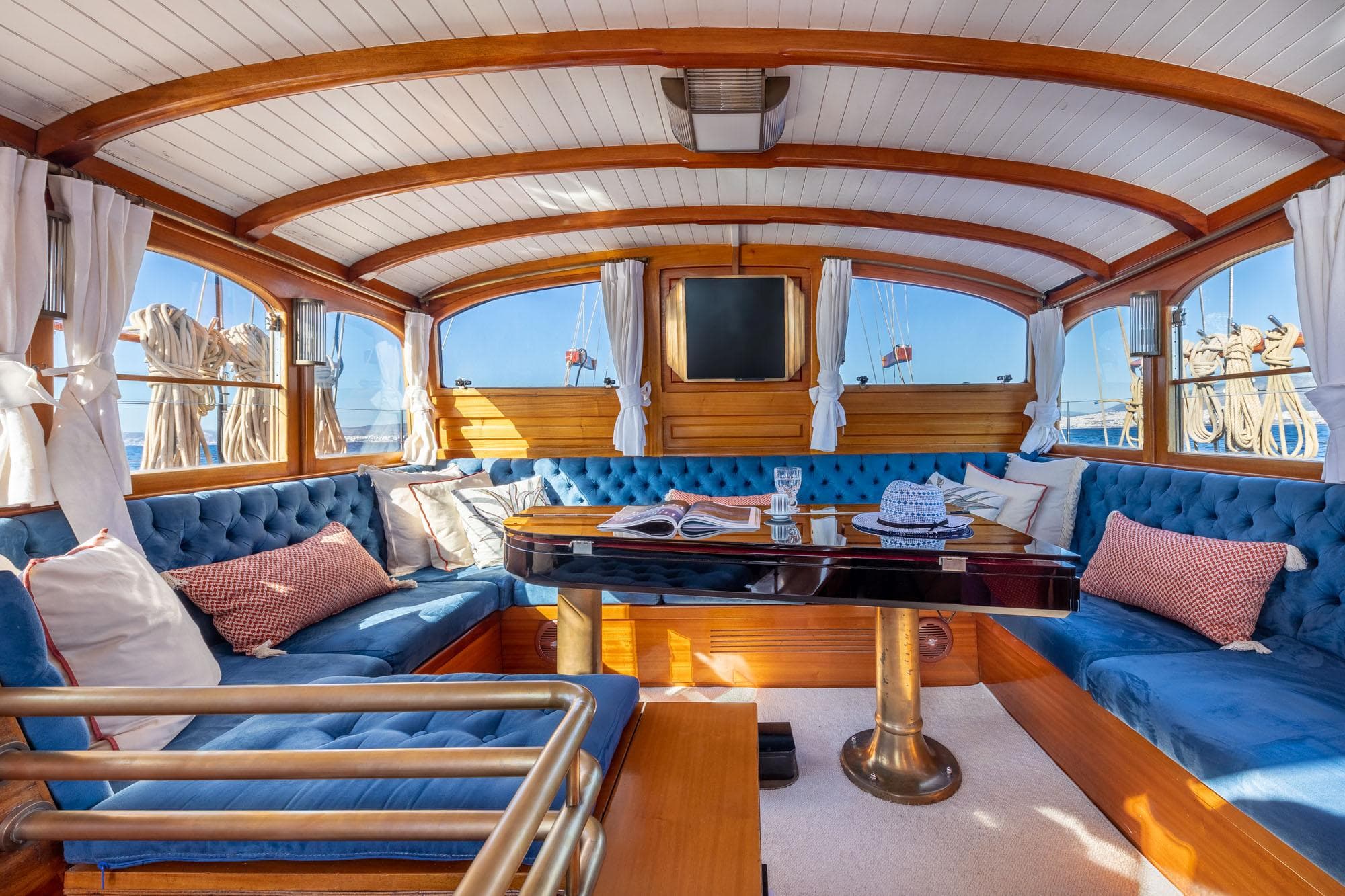 Luxurious interior of 1931 Schooner Navals de Normandie with blue tufted seating and wooden accents.