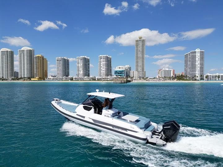 2025 Ranieri CAYMAN 38.0 EXECUTIVE boat cruising near a city skyline.