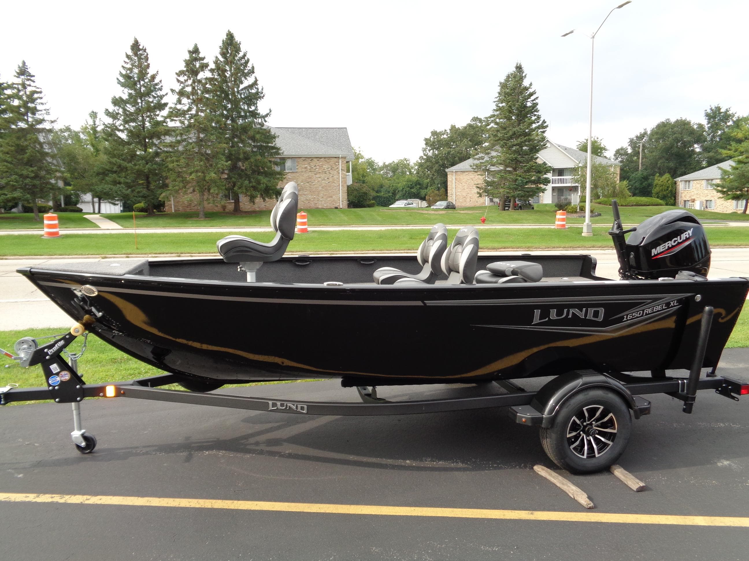 2025 Lund 1650 Rebel XL Tiller boat on trailer, black exterior, parked outdoors.