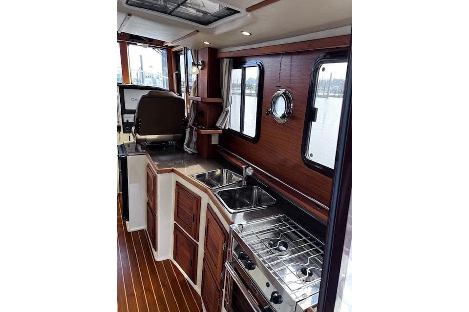 Interior of 2021 Ranger Tugs R-31 CB, featuring a compact kitchen with wood accents.
