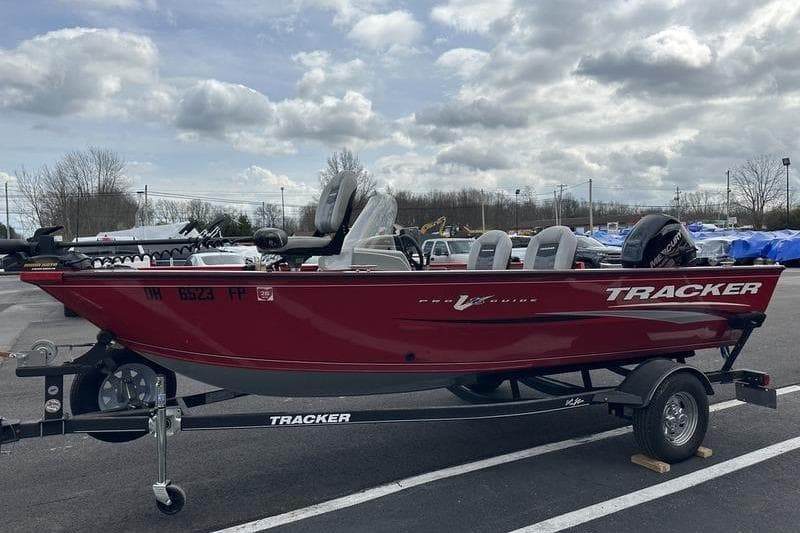 2017 Tracker Pro Guide V-16 SC boat on trailer, parked outdoors under cloudy sky.