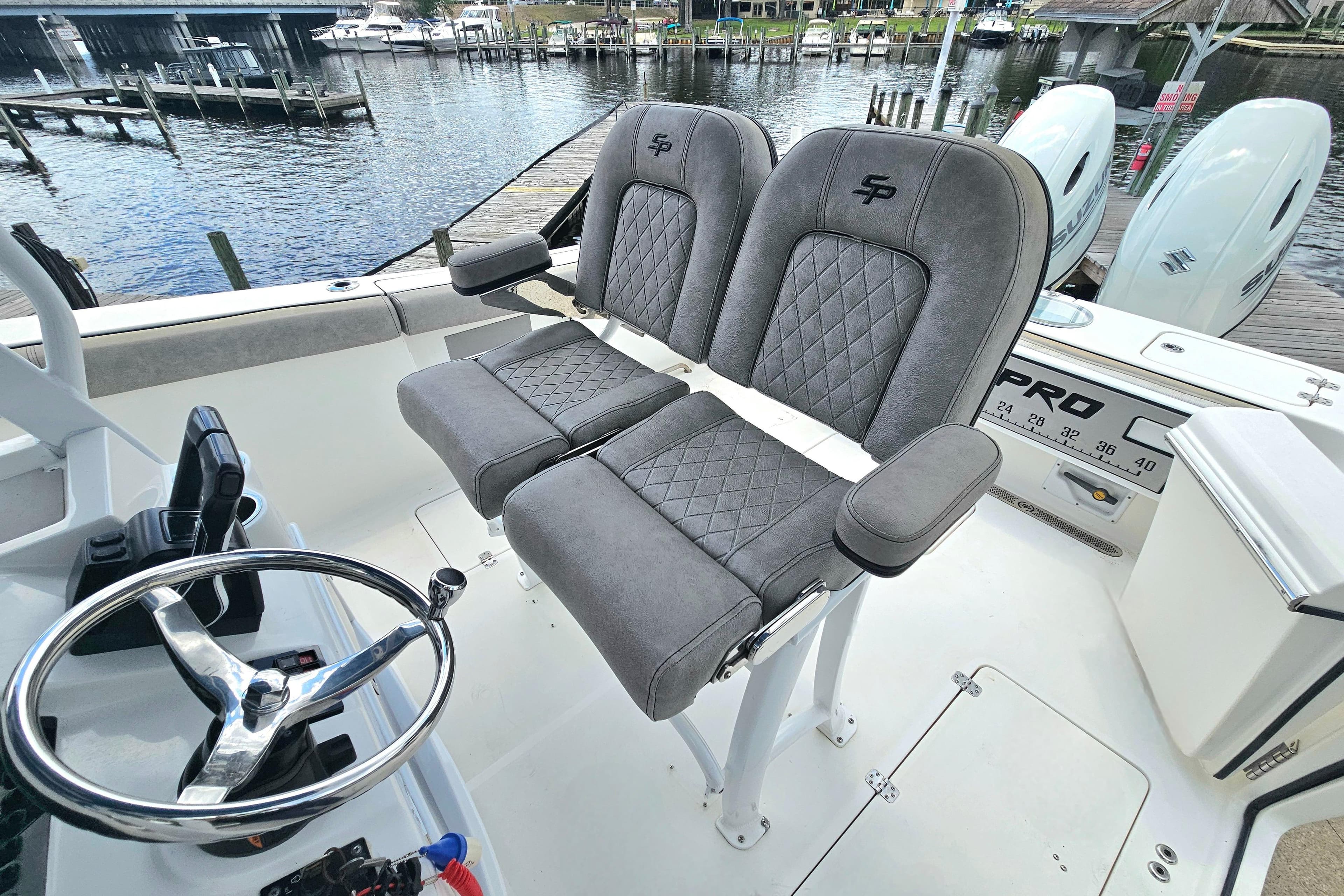 2021 Sea Pro 259 Center Console boat with dual seats and steering wheel, docked by the water.