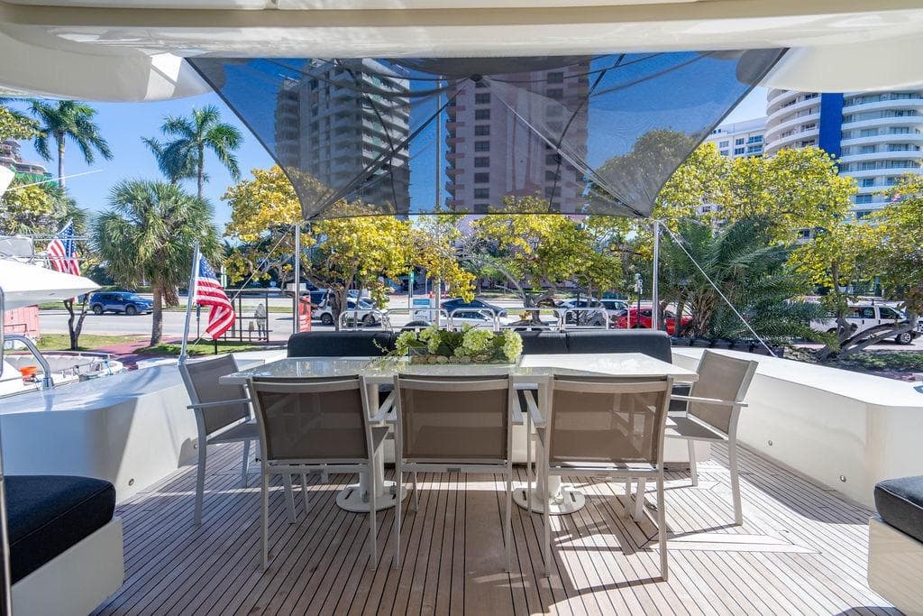 Outdoor dining area on 2007 Arno Leopard 31 yacht, with cityscape and palm trees.