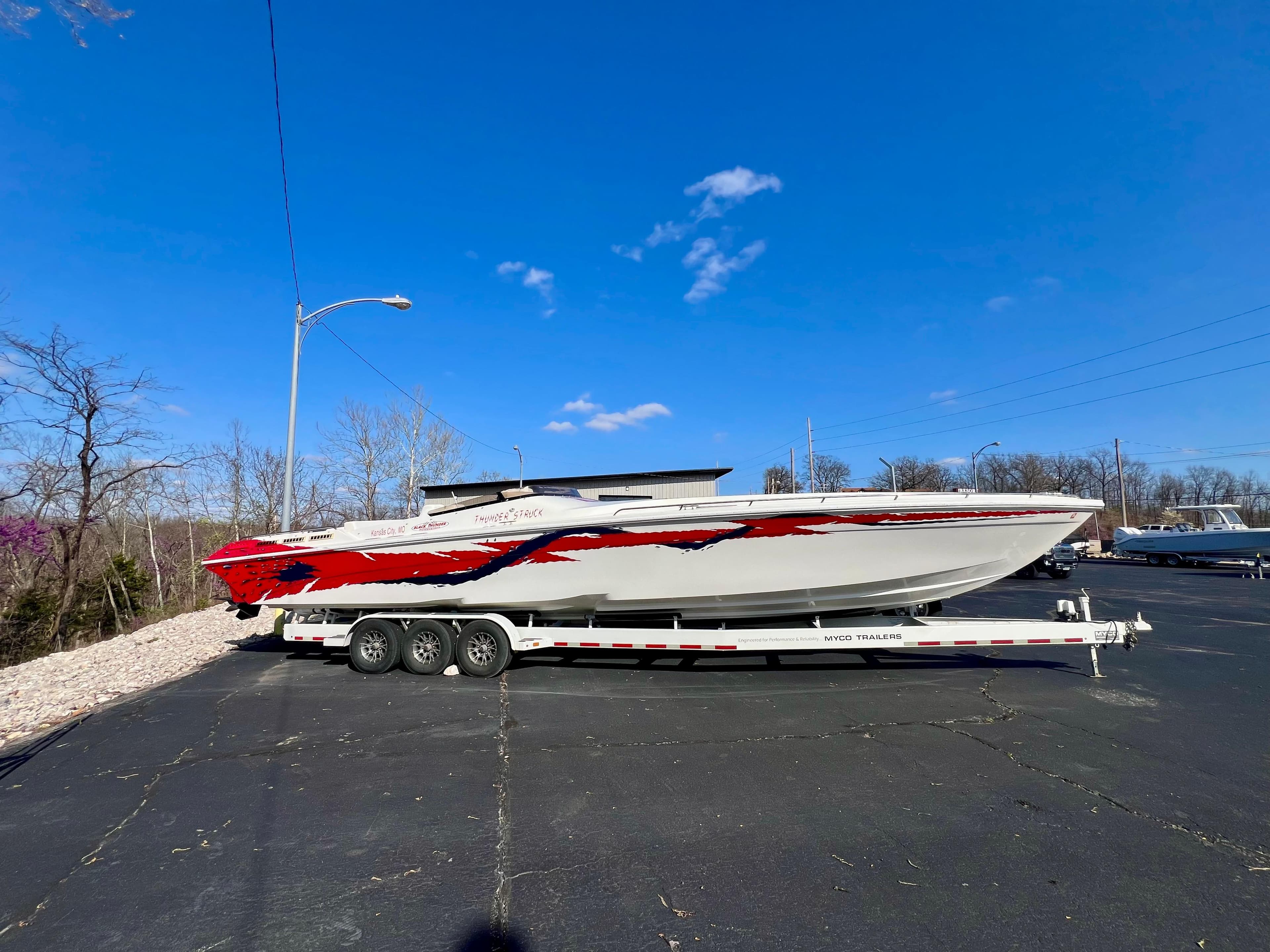 1999 Black Thunder 430 Flat Deck boat on trailer under clear blue sky.
