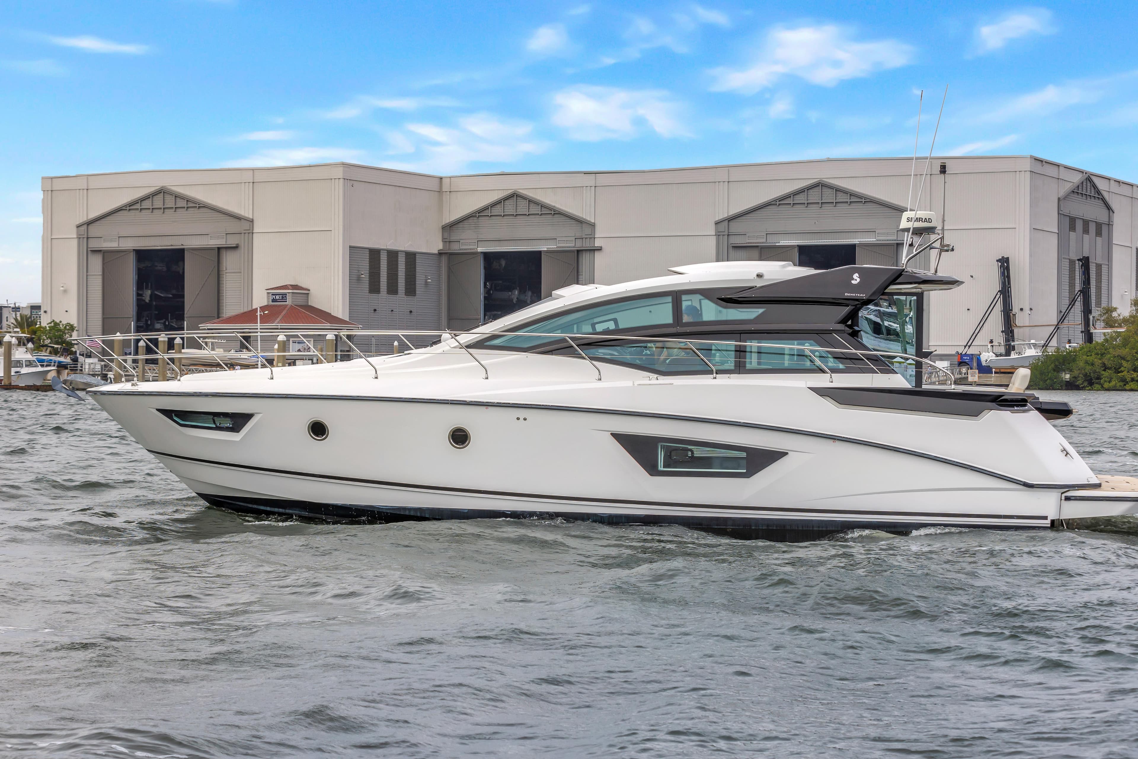 2019 Beneteau Gran Turismo 46 yacht on water, industrial building background.