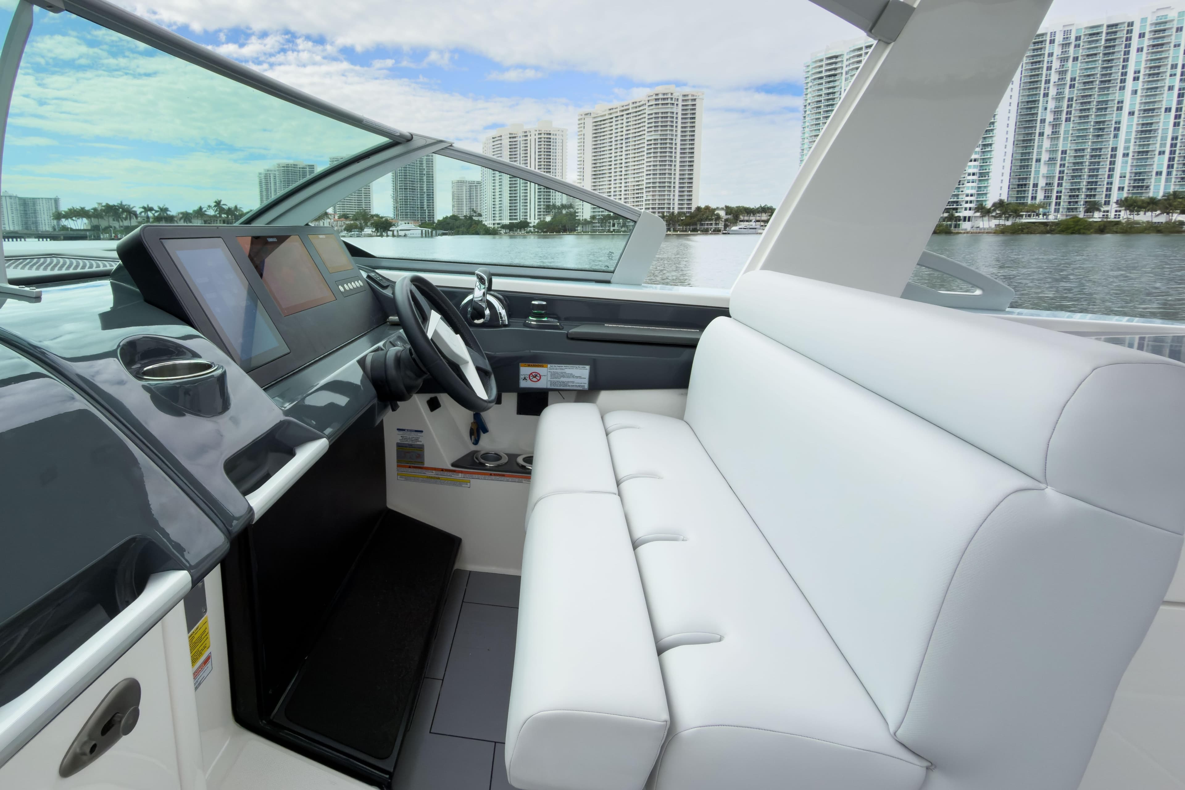2022 Aviara AV32 OB boat interior with modern helm and white seating, cityscape in background.