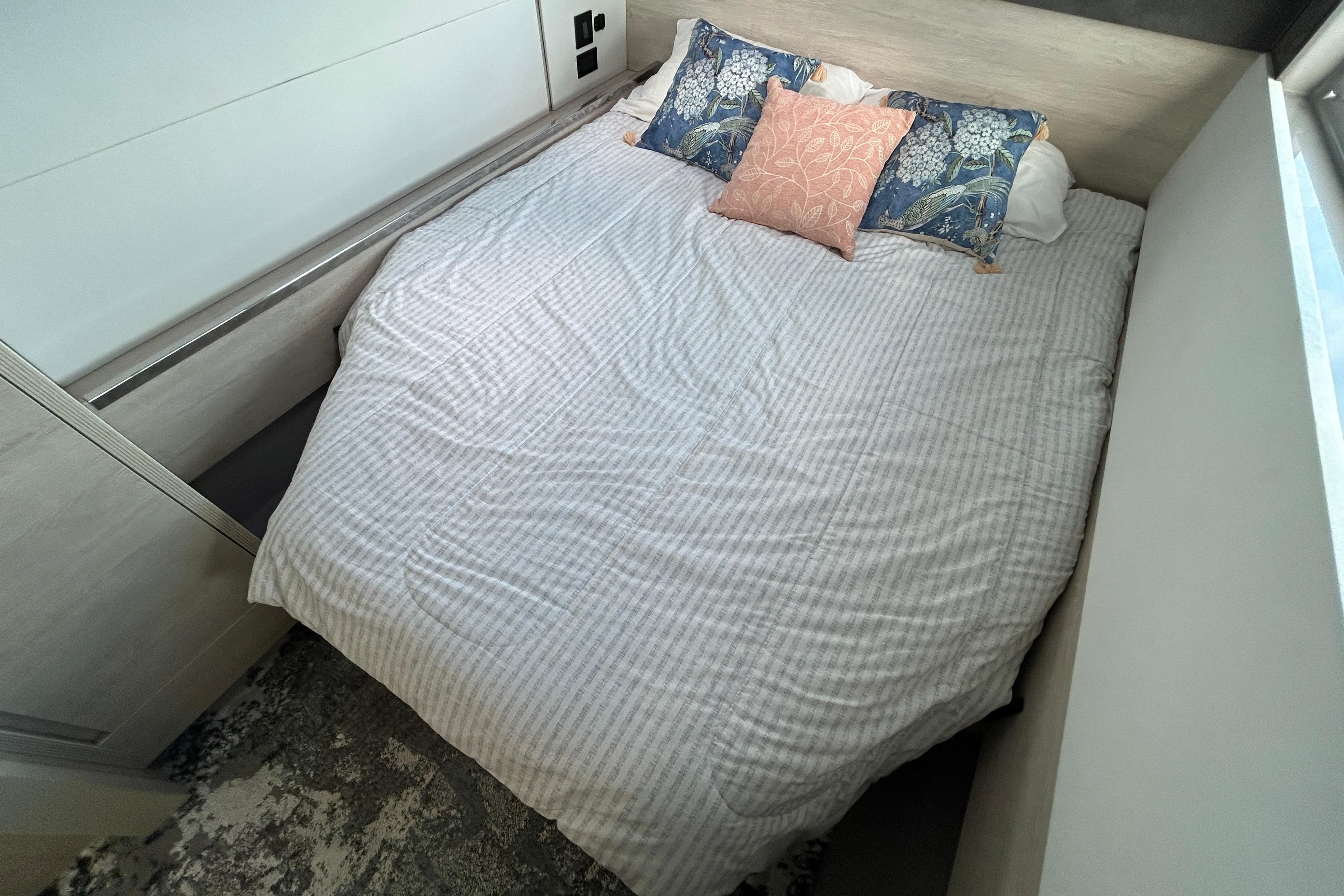 Cozy bedroom in a 2020 Leopard 45 yacht with patterned pillows and striped bedding.