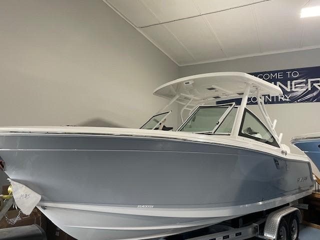2023 Blackfin 252 DC boat in showroom, side view, on trailer.