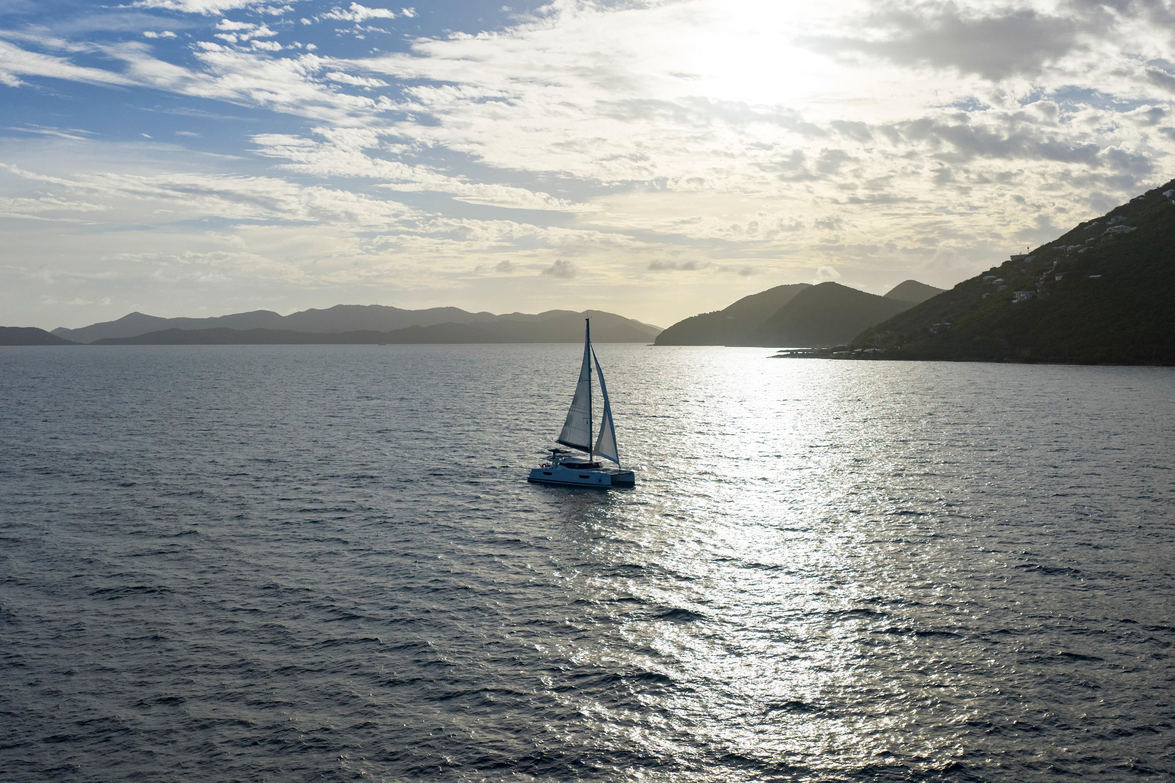 2020 Fountaine Pajot Astrea 42 Catamaran sailing at sunset on open sea.