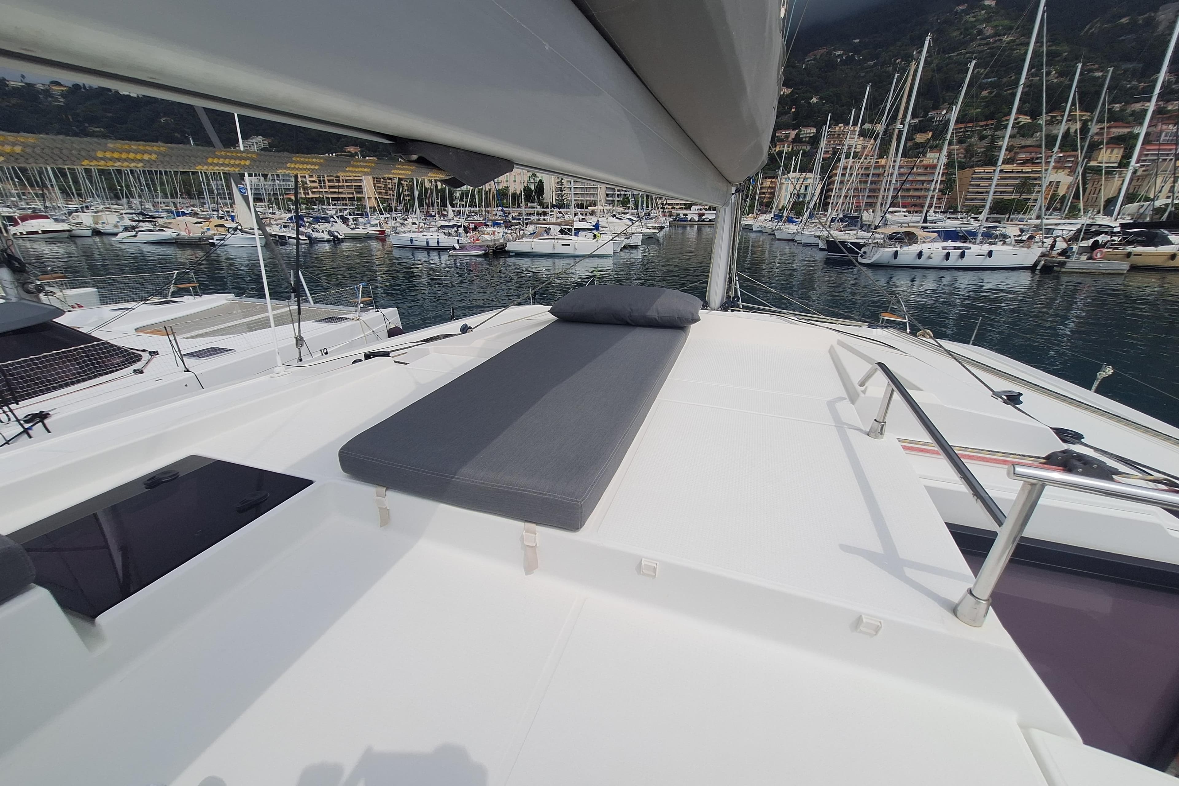 Fountaine Pajot Saona 47 catamaran deck with sunbed, docked in marina, 2021 model.