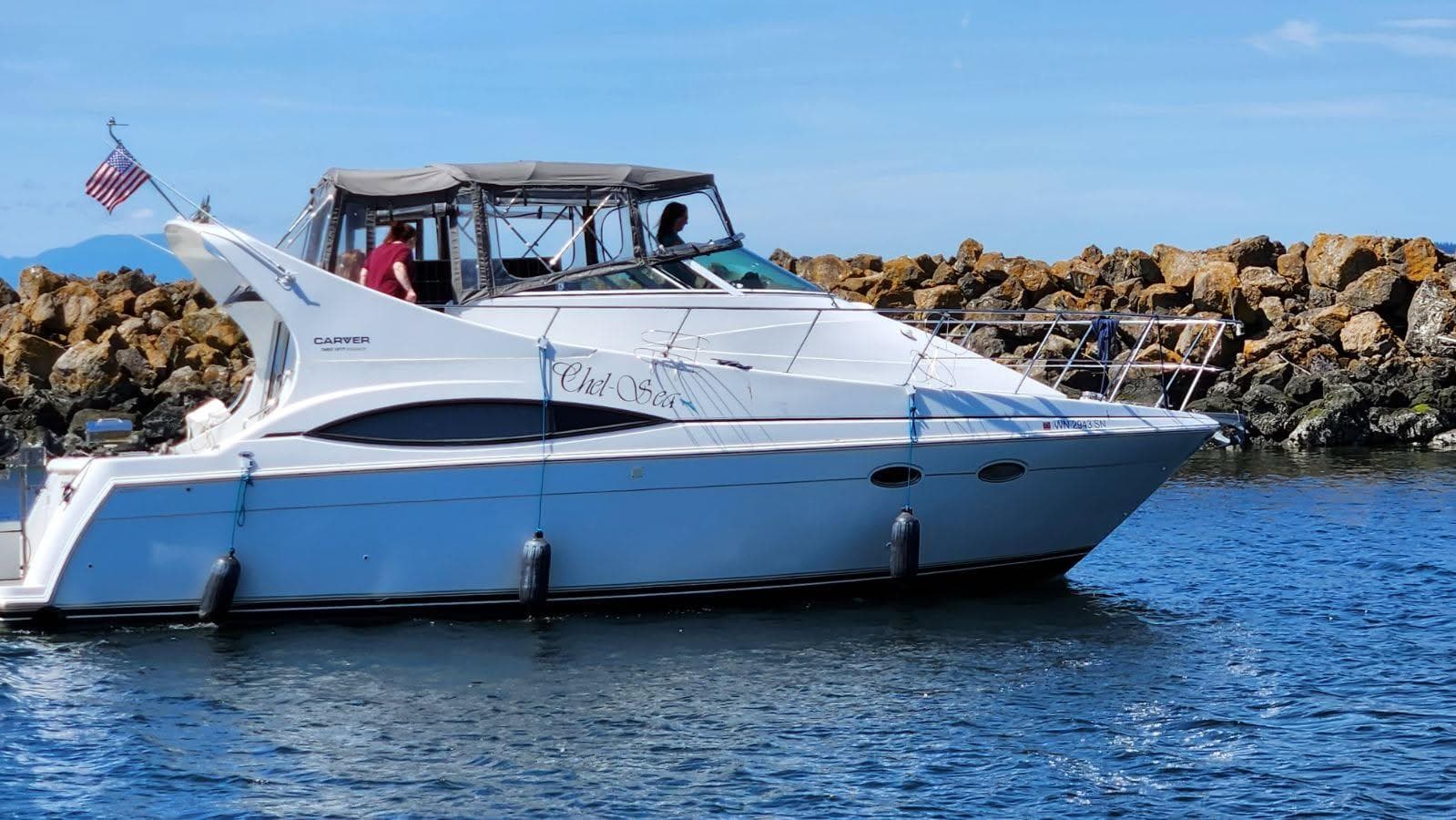 1997 Carver 350 Mariner yacht cruising near rocky shoreline.