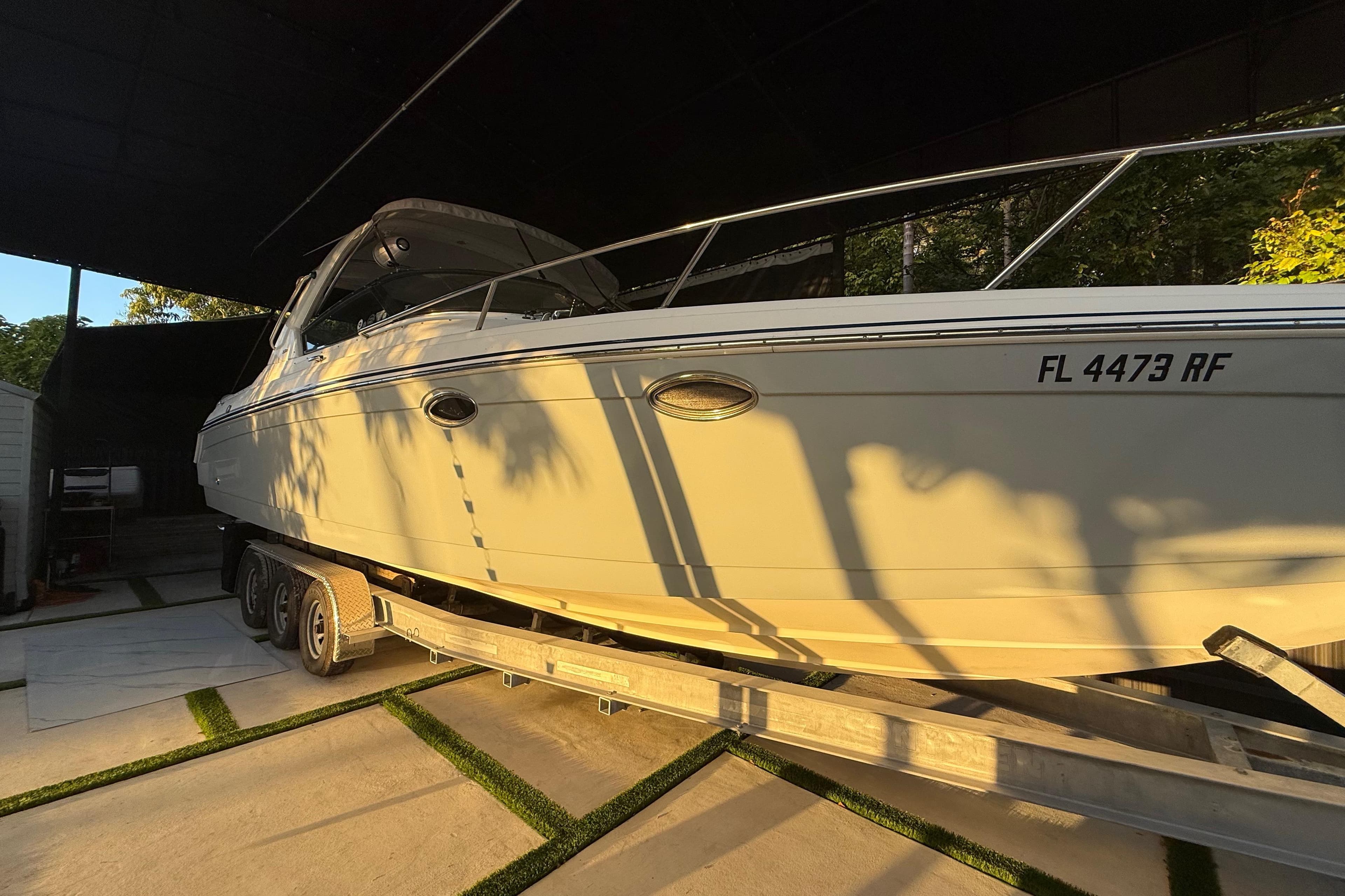 2005 Formula 330 Sun Sport boat on trailer, parked in shaded area.