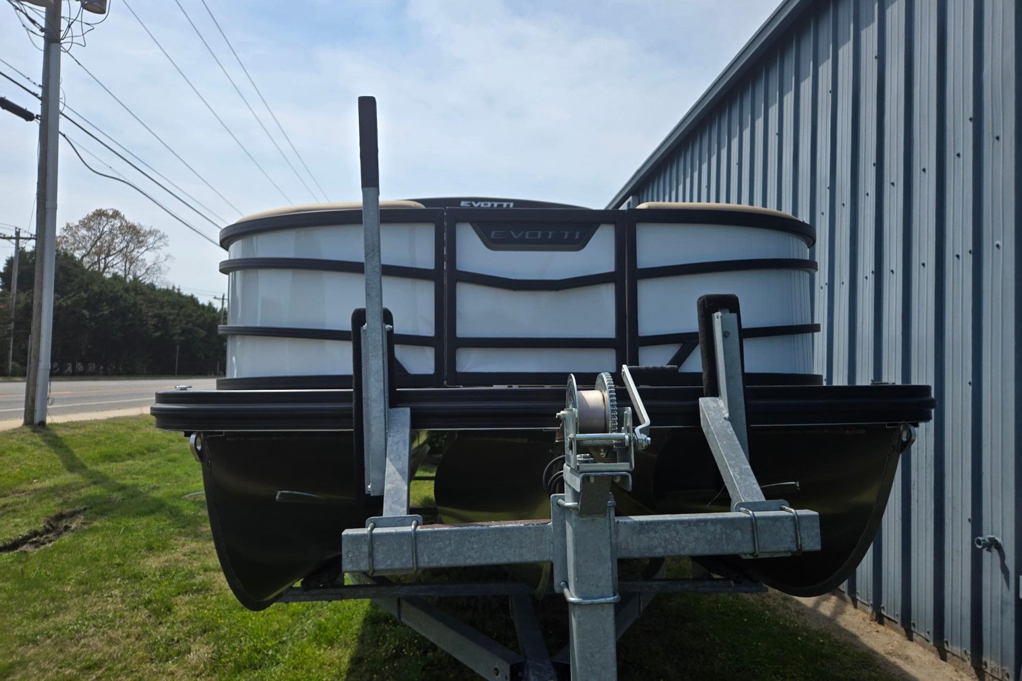 Evotti 523QL 2026 pontoon boat on trailer near metal building.