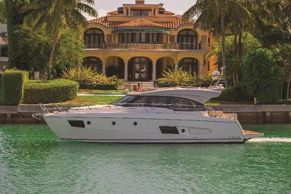 2015 Bavaria 420 Virtess Coupe yacht cruising near a luxurious waterfront mansion.
