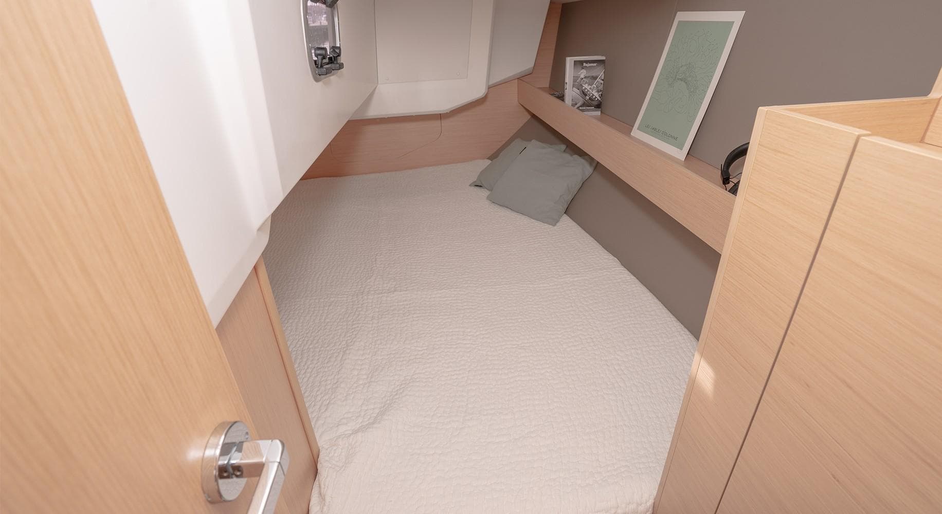 2025 Beneteau Oceanis 30.1 cabin interior with cozy bed and wooden finish.