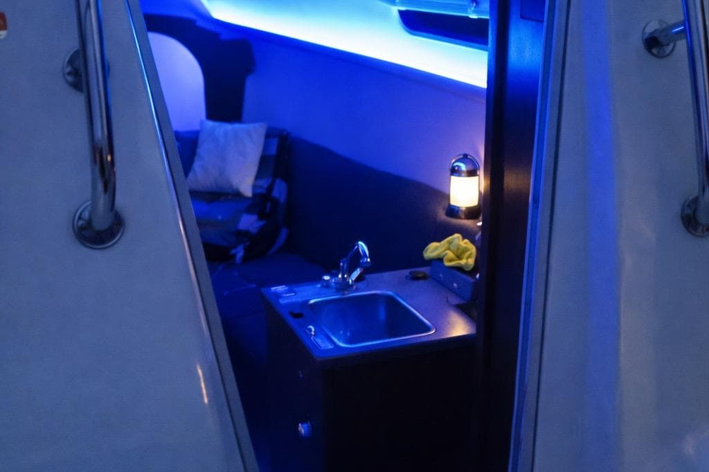 Interior of 2008 Hunter 27 sailboat with sink and ambient blue lighting.