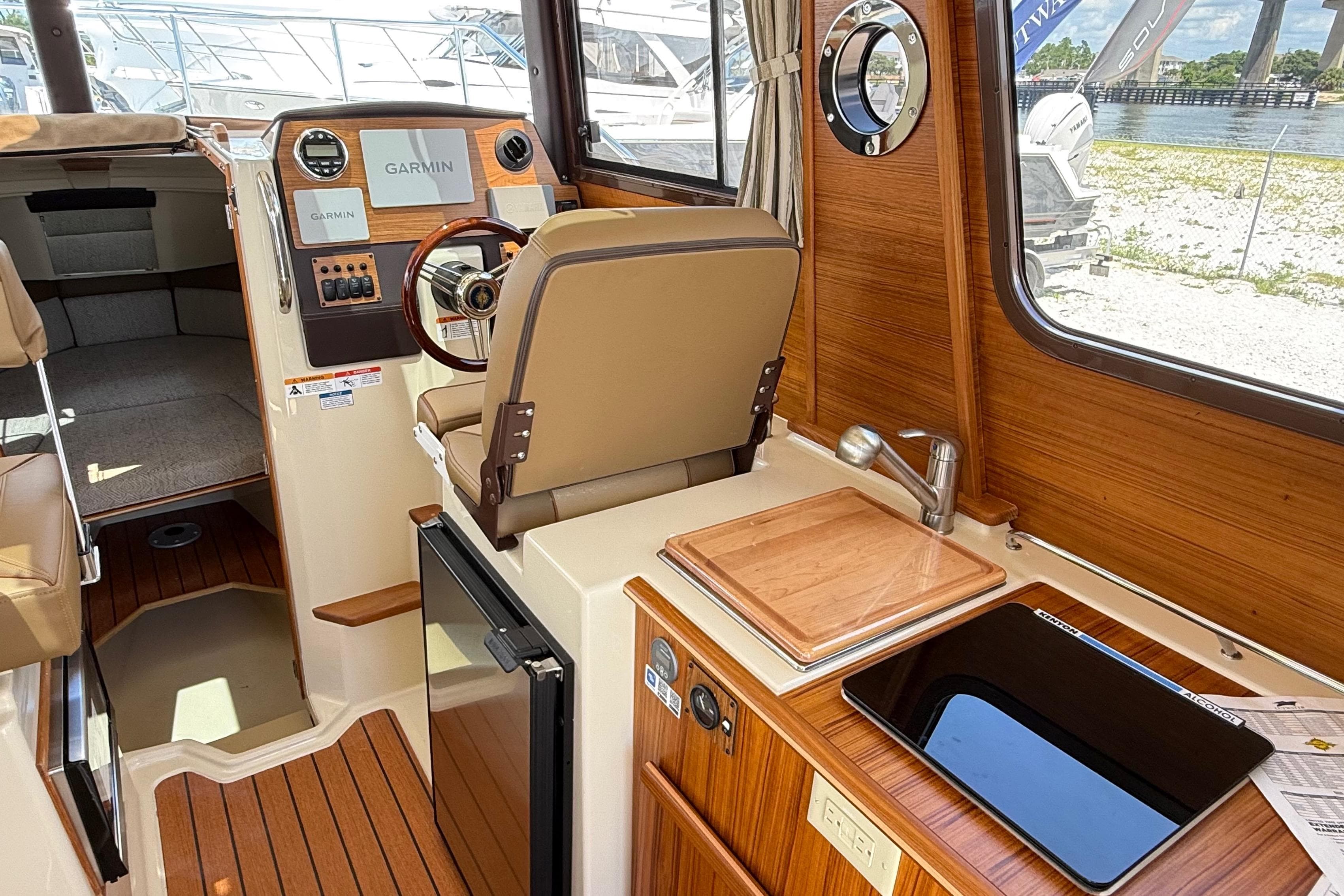 Interior of 2025 Ranger Tugs R-23 boat with helm, sink, and seating area.