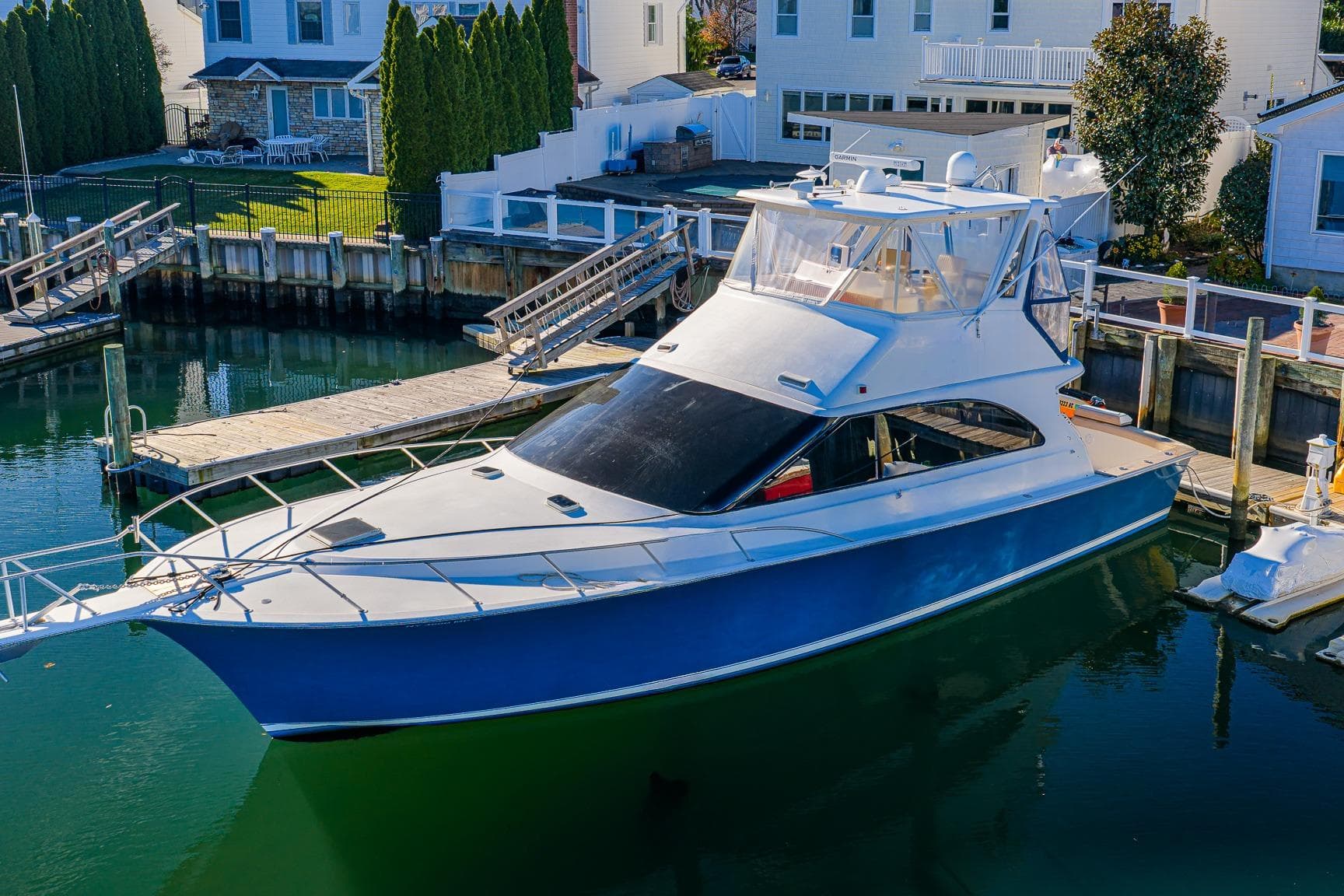 1998 Ocean Yachts 48 Super Sport docked in a marina, surrounded by waterfront homes.