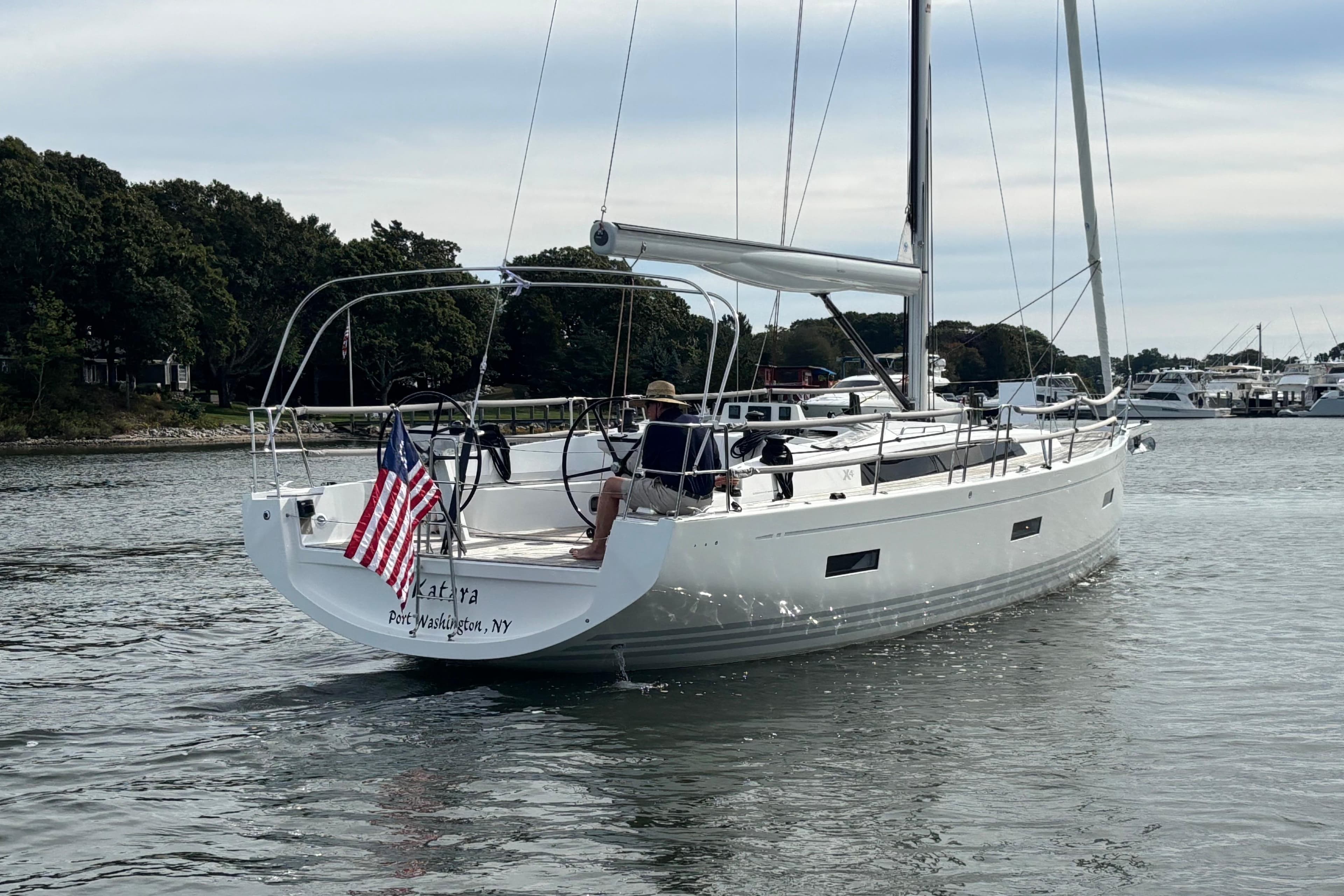 2023 X-Yachts X4³ MkII sailing in a calm harbor, displaying an American flag.