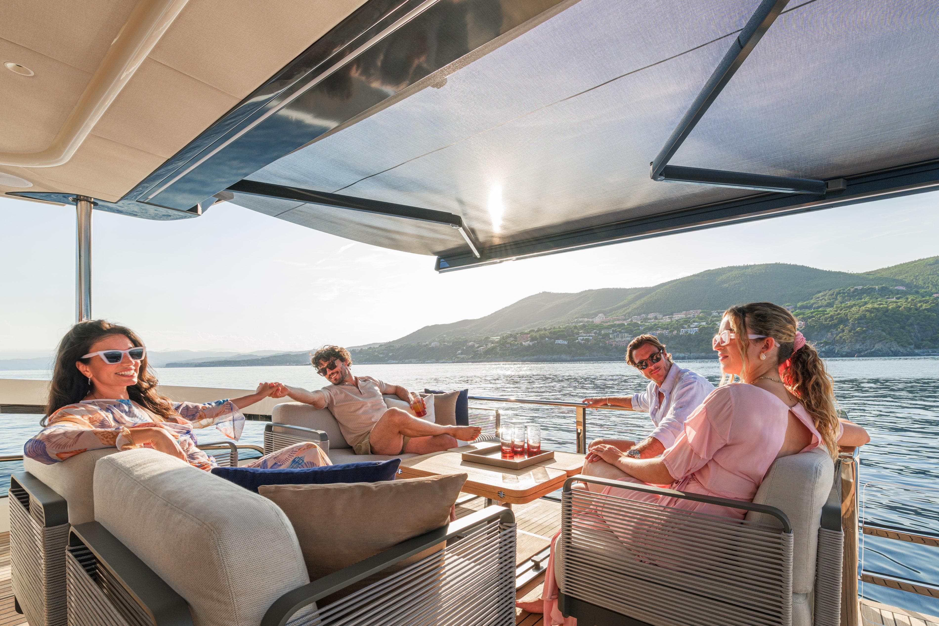 People relaxing on a 2026 Absolute 62' Navetta yacht, enjoying scenic ocean views.