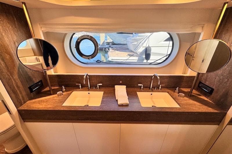 Luxurious bathroom in 2026 Azimut Grande Magellano 25 Metri yacht with dual sinks and porthole view.