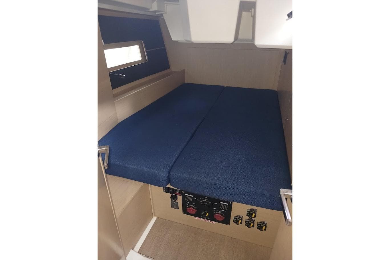 Interior cabin of 2020 Beneteau Oceanis 46.1 yacht with blue cushions and control panel.