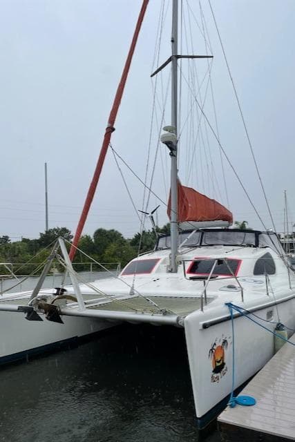2001 Voyage Maxim catamaran docked, featuring red sail and sleek design.